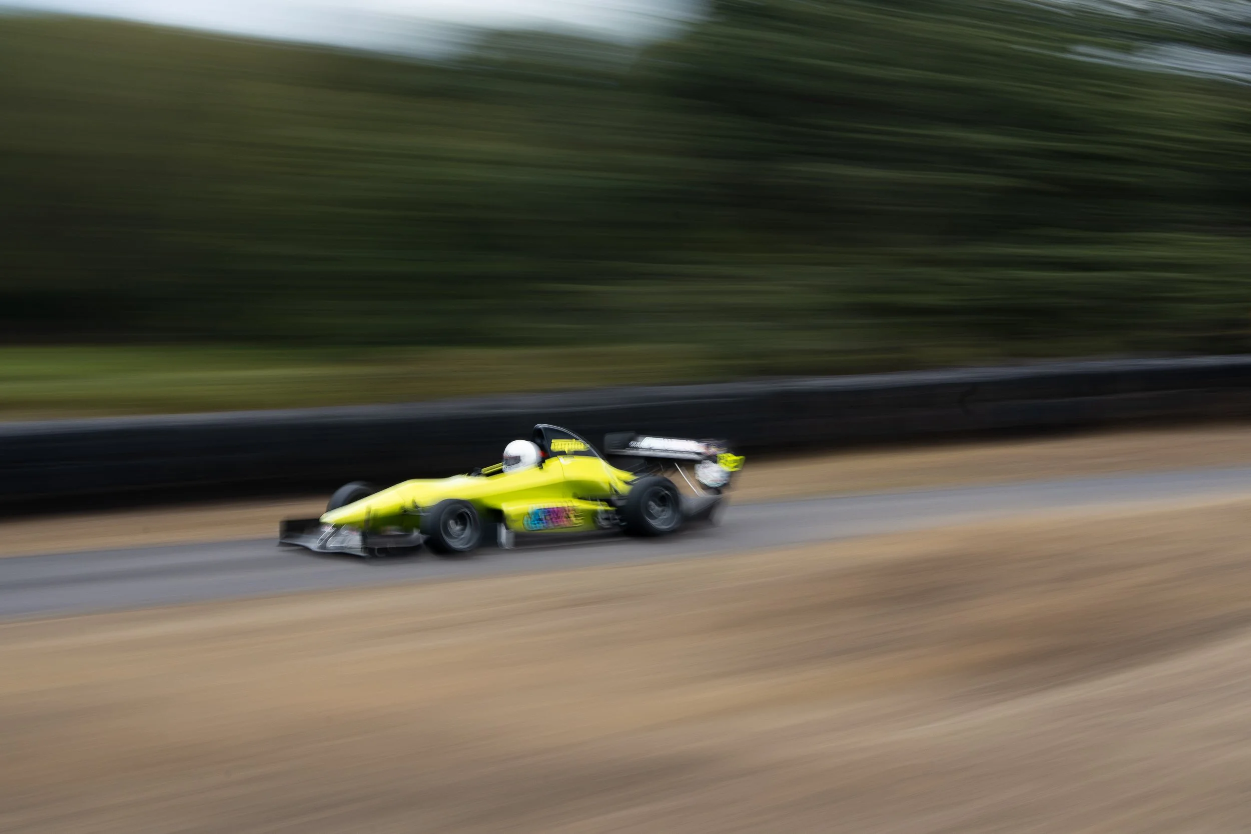 Yellow single-seater racing car with motion blur climbing the course at Loton Park British Hill Climb Championship