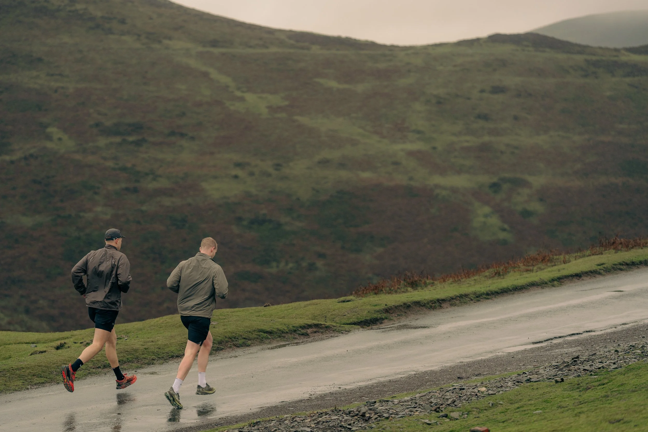Two runners on the road with rolling hills stretching into the distance for the Torra Performance Long Mynd campaign