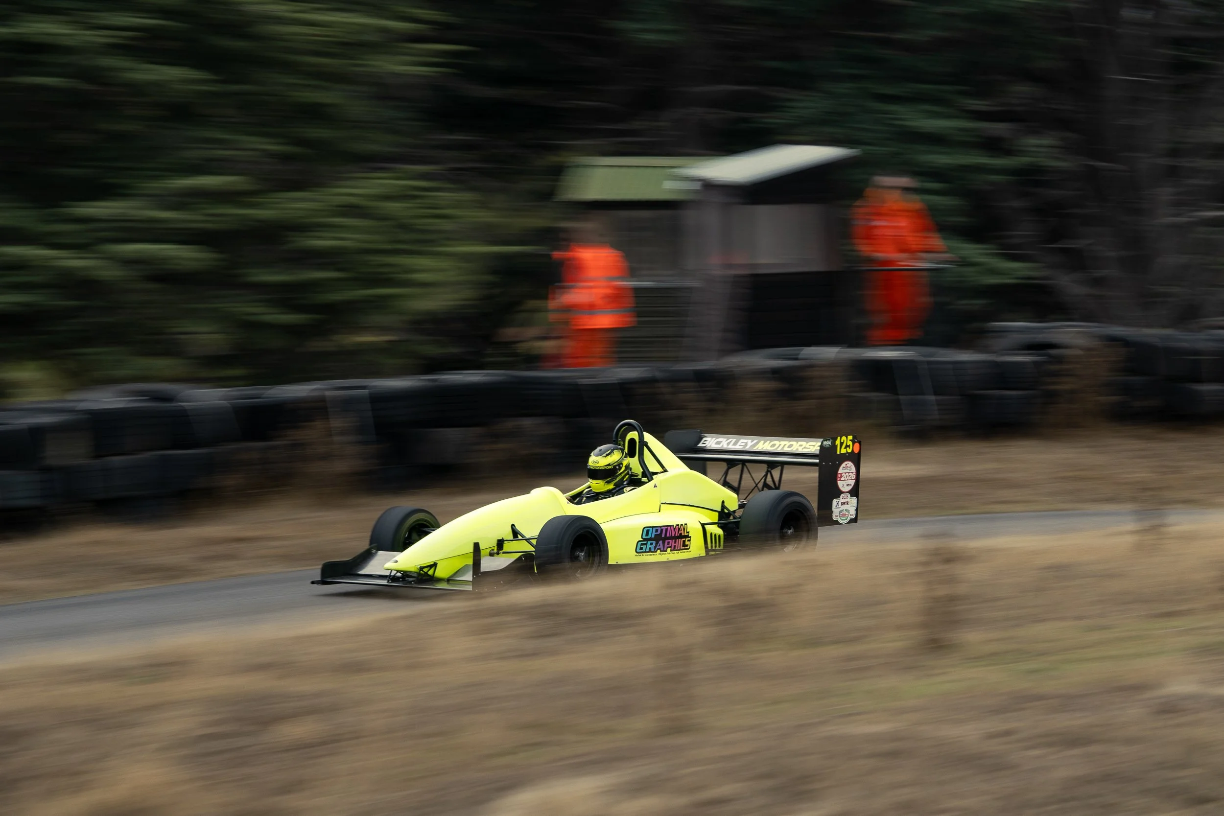 Single-seater racing car cornering with trackside marshals watching at Loton Park British Hill Climb Championship