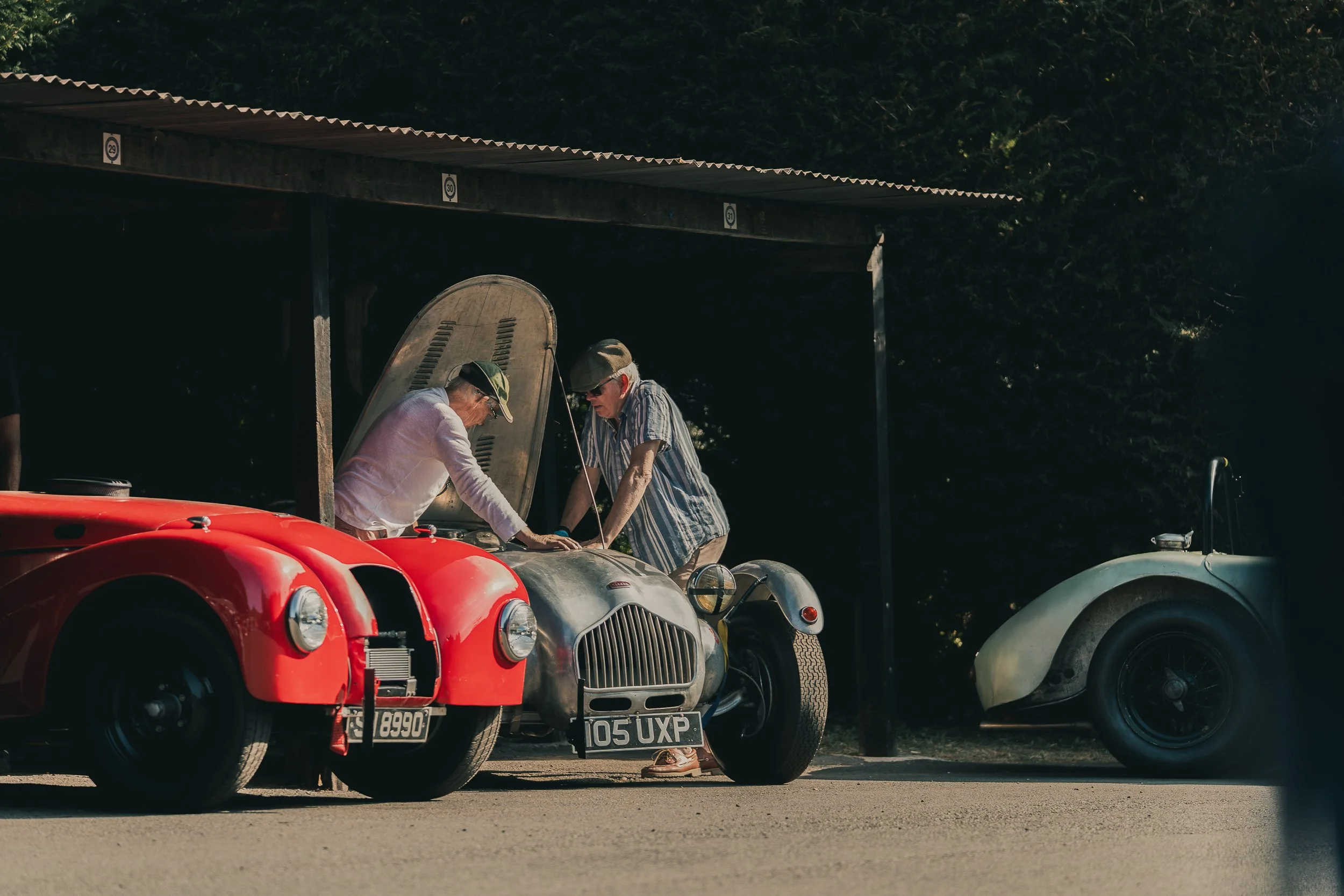 Mechanics working on a vintage red racing car in the garage at Shelsley Walsh Classic Nostalgia