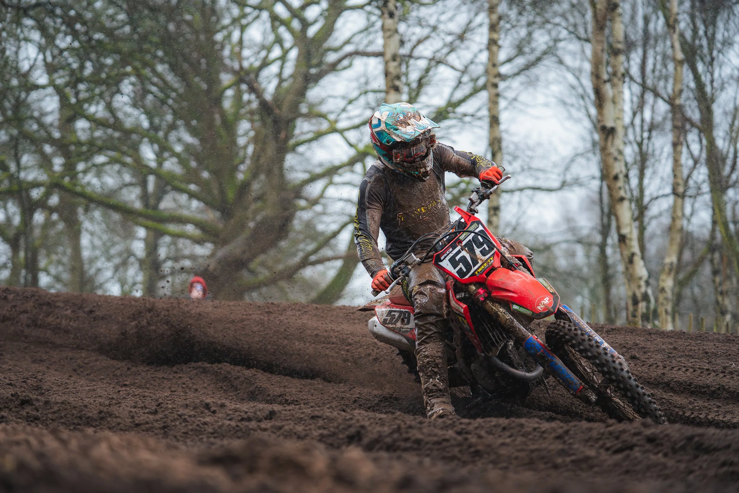 Motocross rider leaning through a wooded section of the track at the British Motocross Championship Hawkstone International
