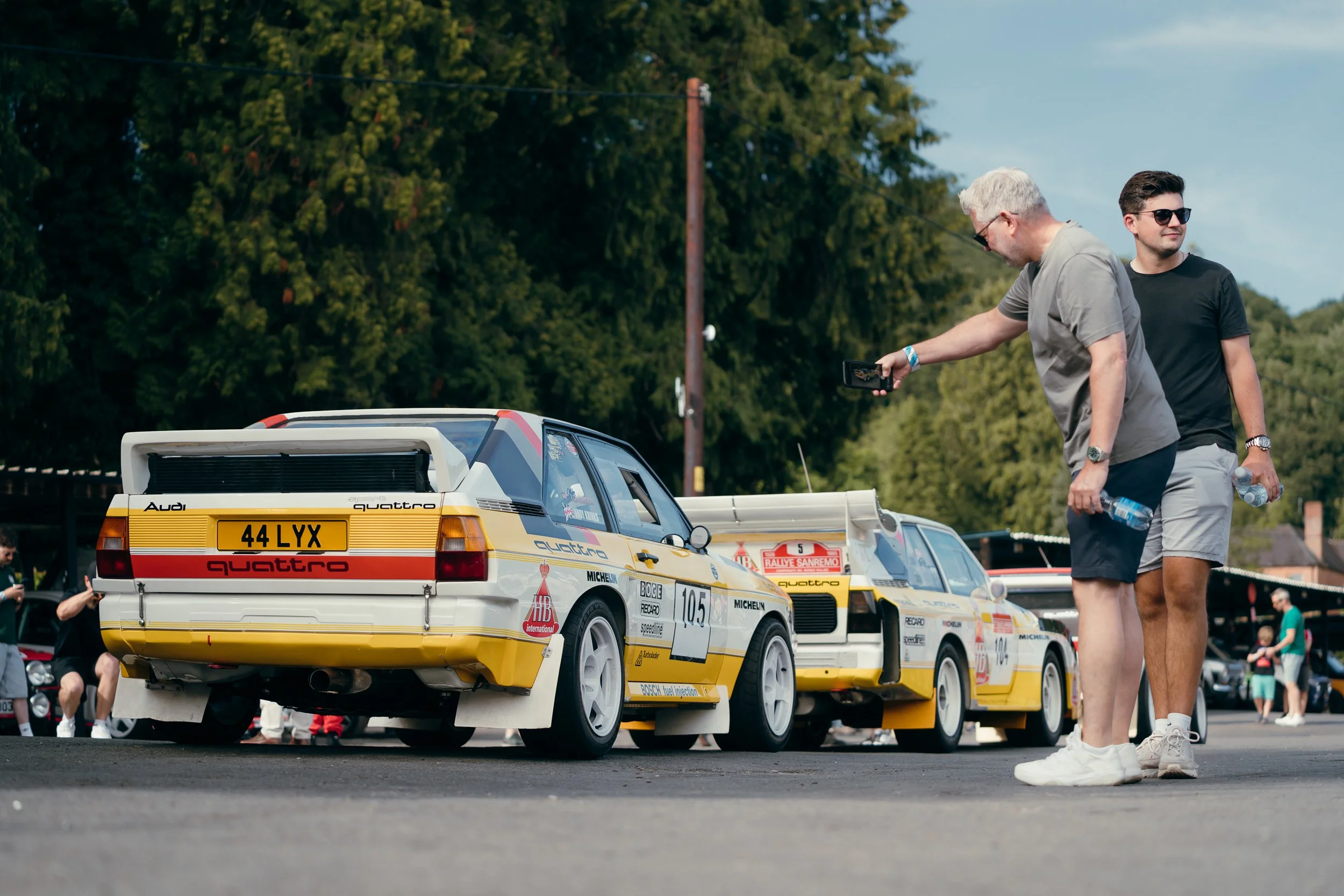 Spectators chatting beside a row of classic Audi Quattro rally cars on display at Shelsley Walsh Classic Nostalgia