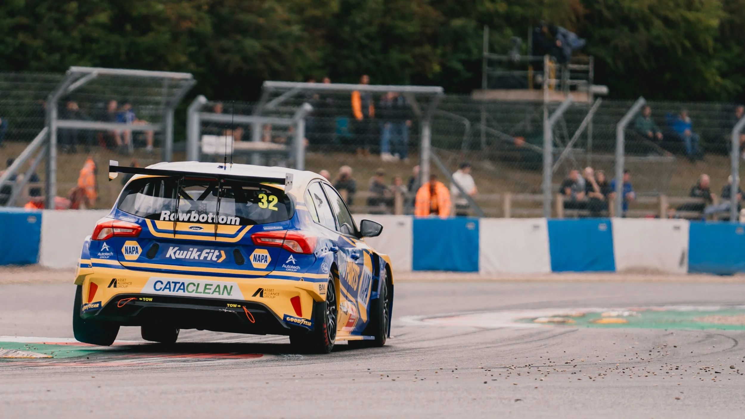 A race car on a track with spectators in the background.