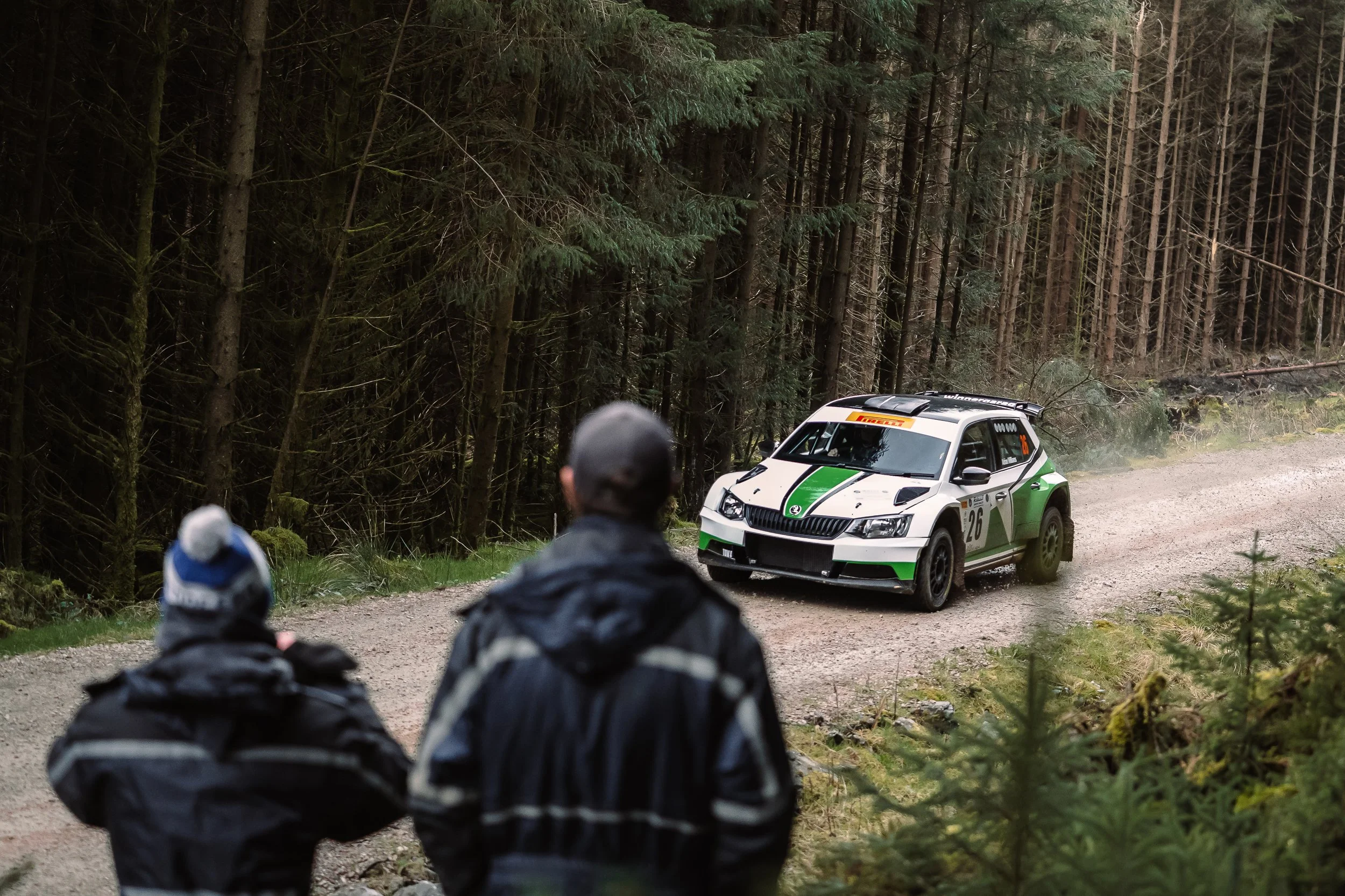 Spectators watching a Skoda rally car pass on the forest stage at Rally North Wales