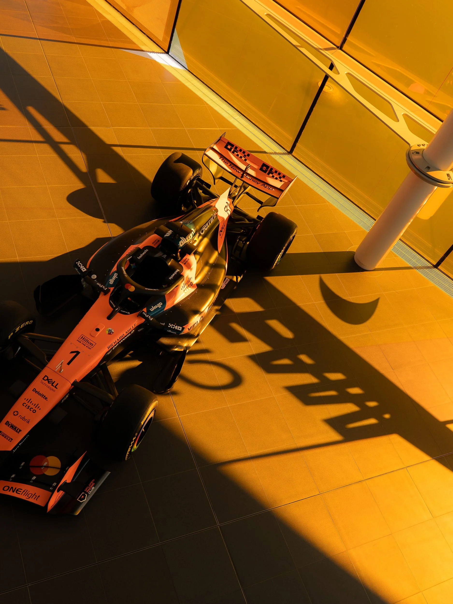 Historic orange McLaren Formula One car on display in golden light at the McLaren Technology Centre
