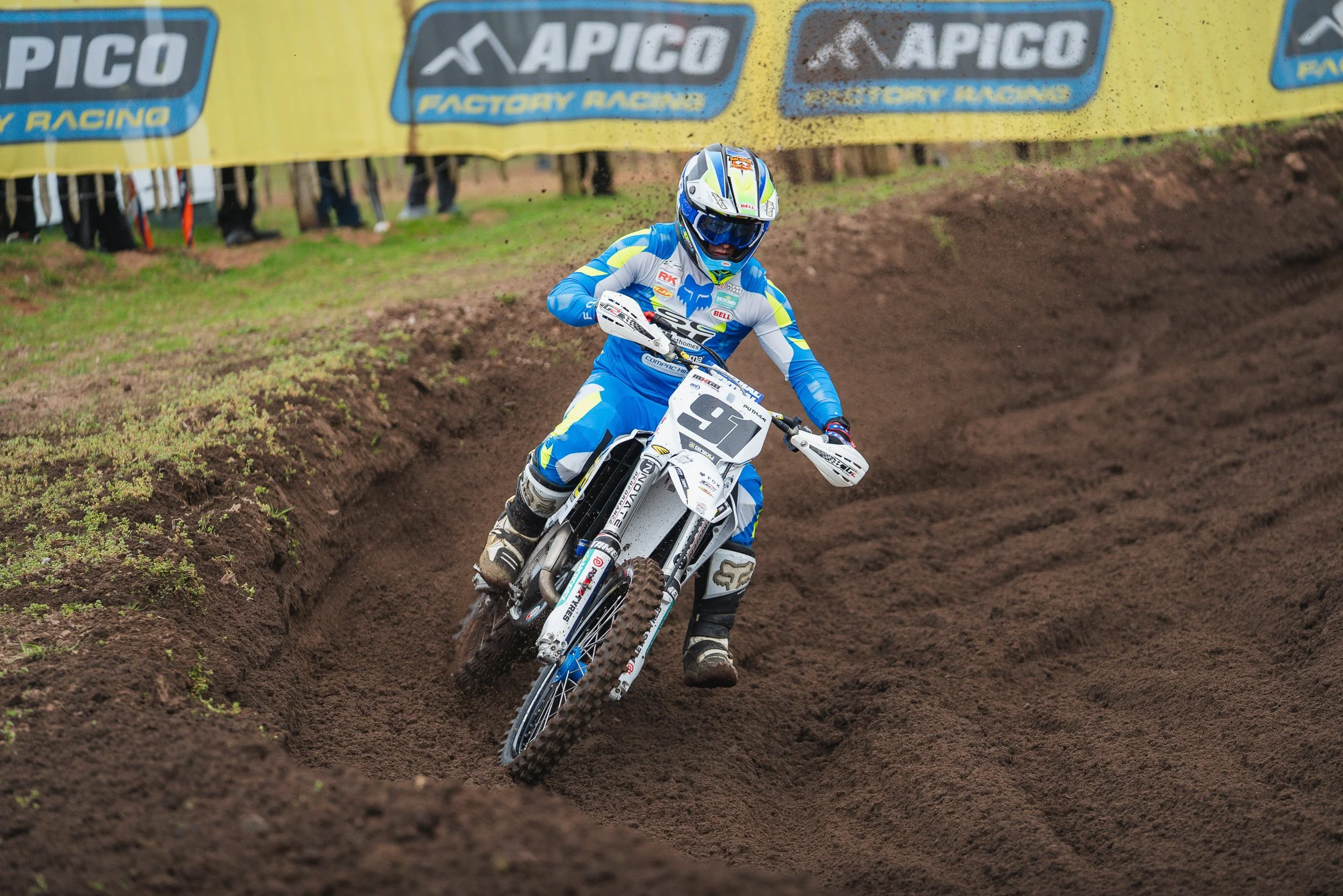 Motocross rider leaning into a corner past the Apico banner at the British Motocross Championship Hawkstone International