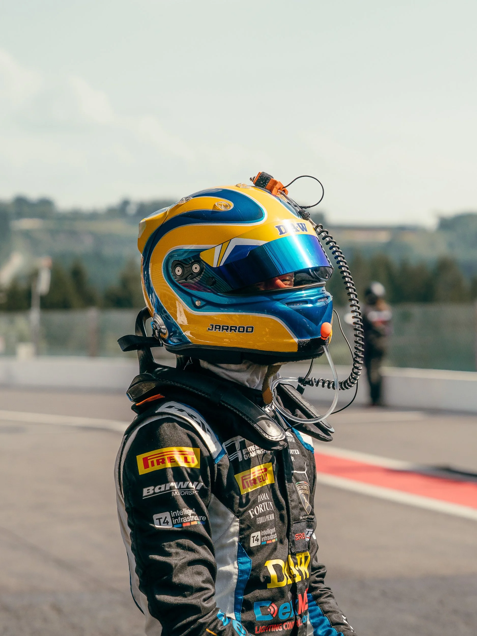 Close-up profile of a British GT driver's yellow and blue racing helmet with radio microphone at Spa-Francorchamps