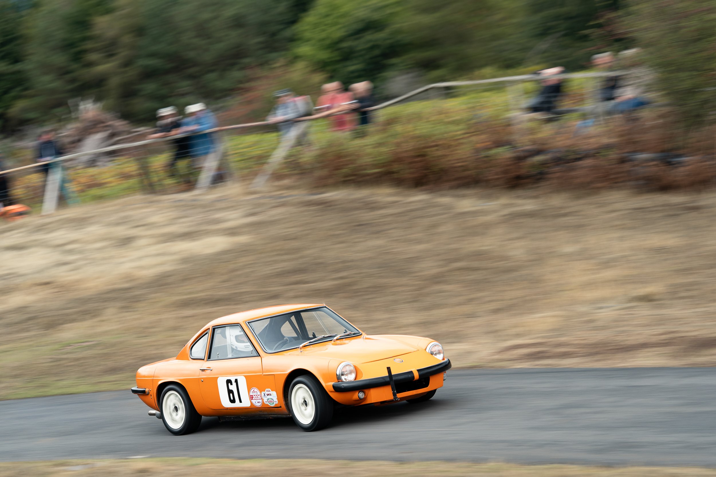 Orange classic sports car cornering hard with spectators watching from the bank at Loton Park British Hill Climb Championship