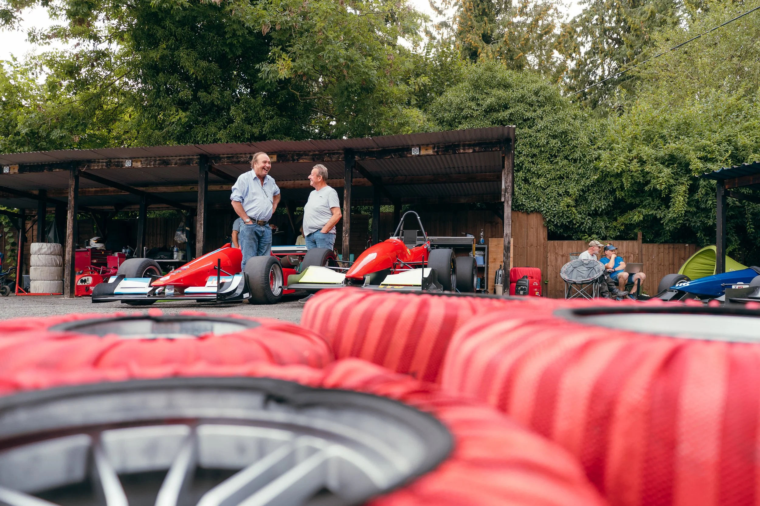 Red tyre safety barriers lining the paddock with race cars parked behind at Shelsley Walsh Championship Challenge