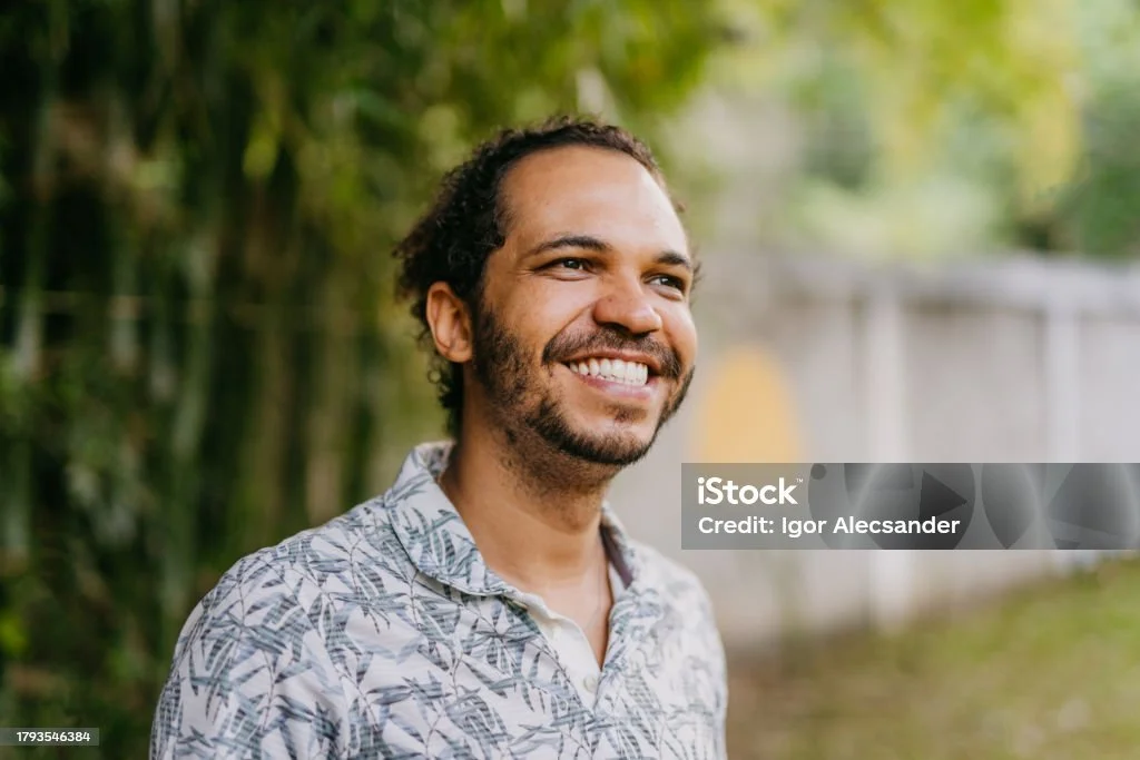 Smiling man outdoors with greenery in background