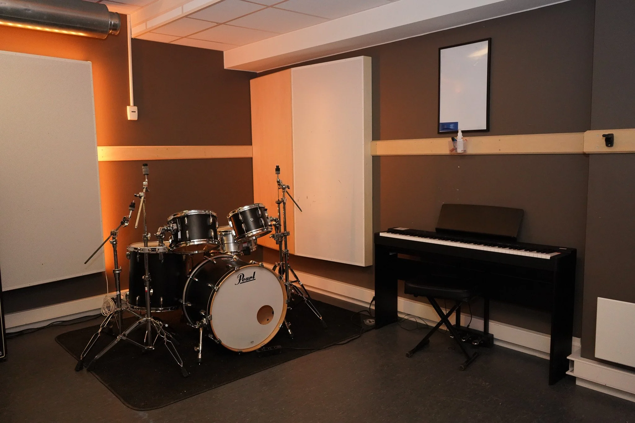 Musikklokker og keyboard i et rom, sannsynligvis et øvingsrom for band.