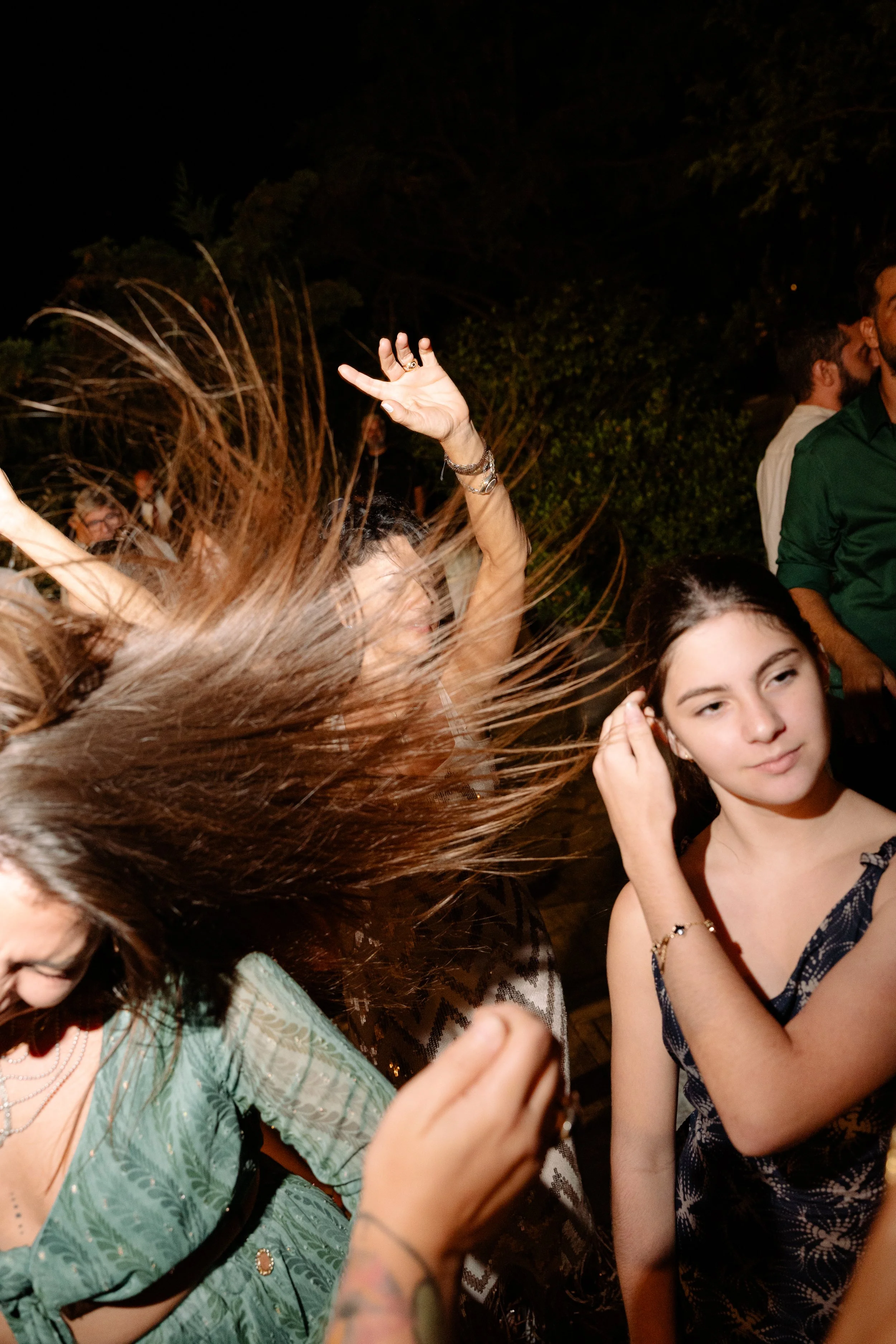 People dancing at night, with one woman flipping her hair.