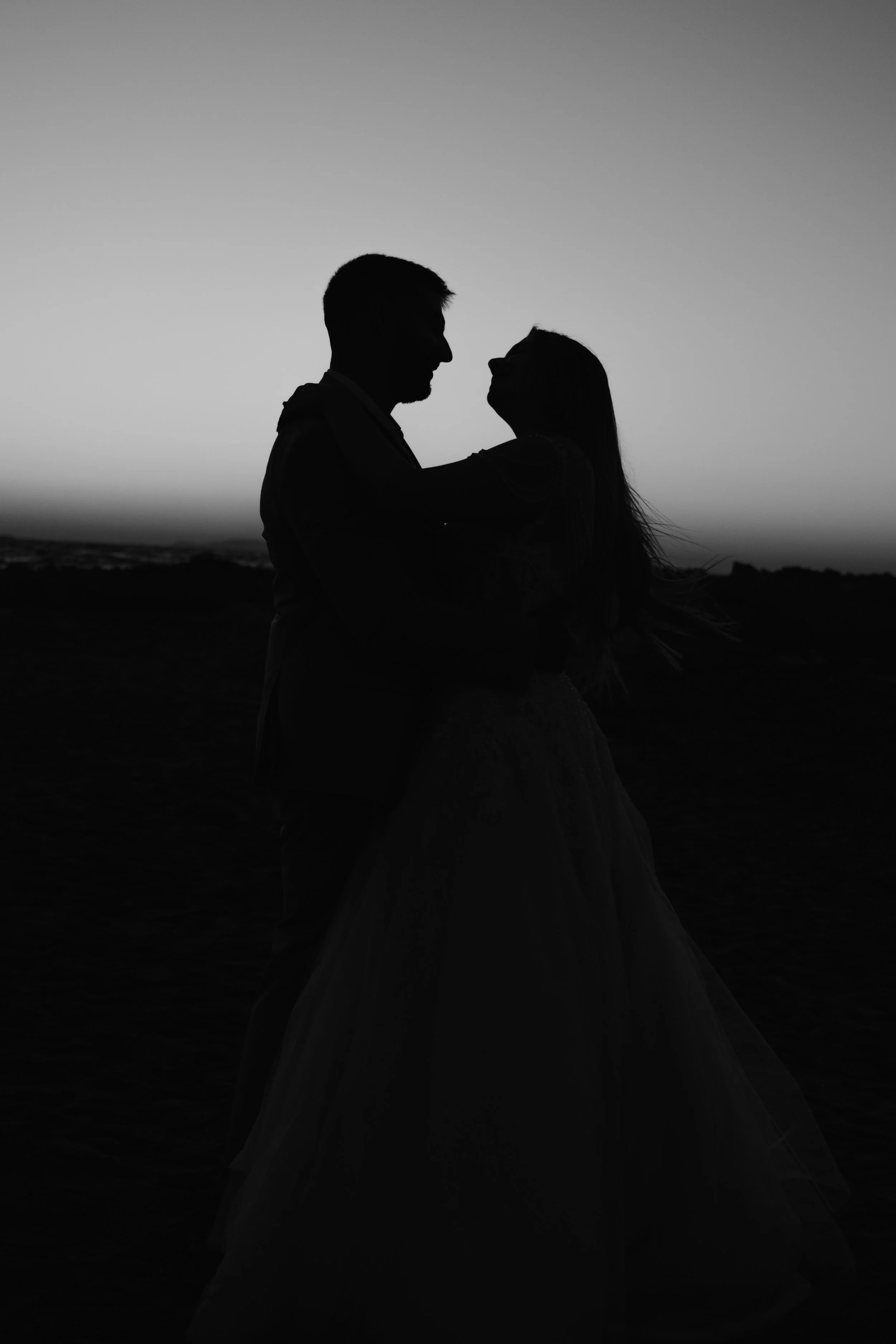 Silhouette of a couple dancing outdoors at sunset.