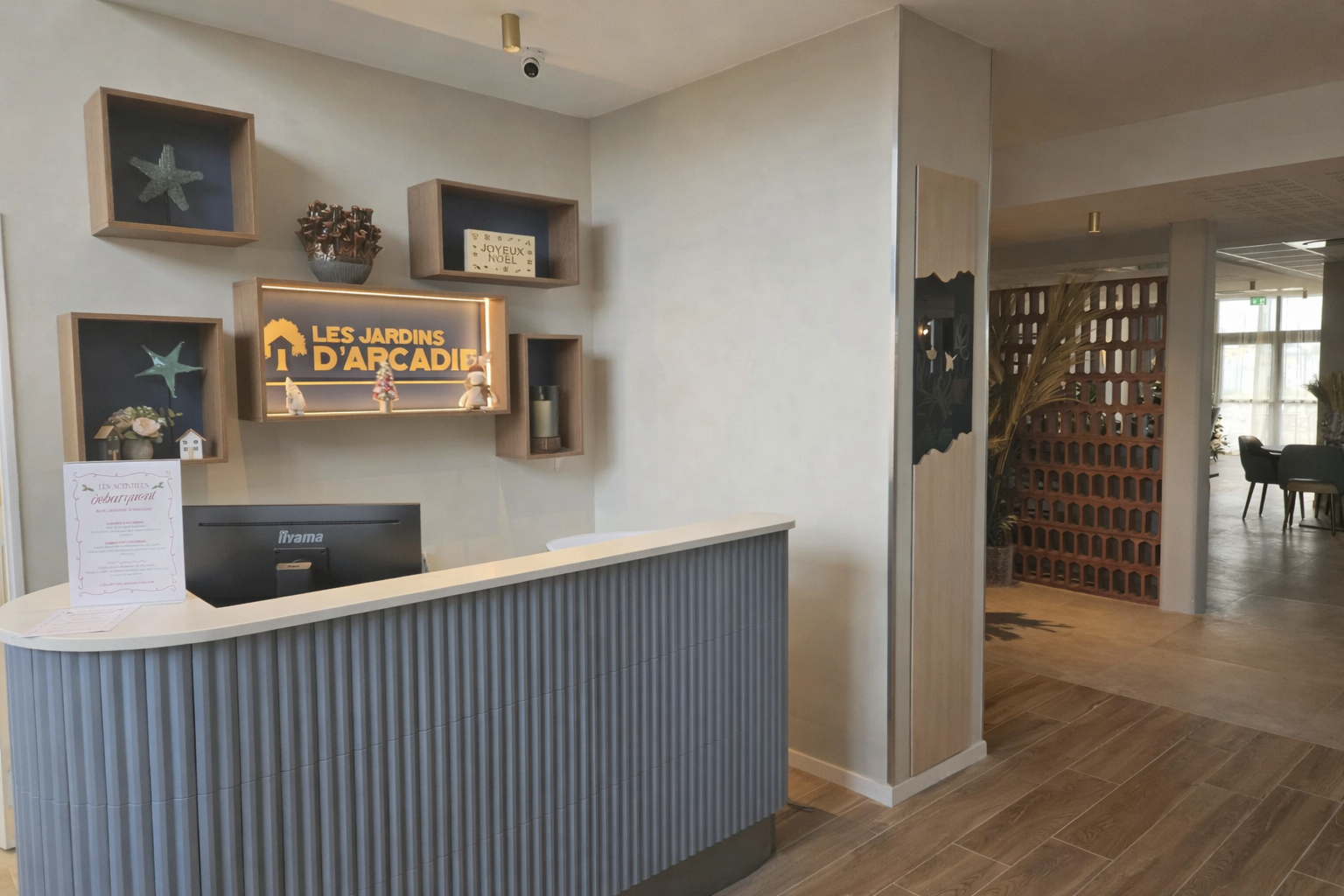 Accueil avec un comptoir bleu, des étagères, avec des étoiles de mer, de la décoration et le logo. Un claustra en brique au fond.