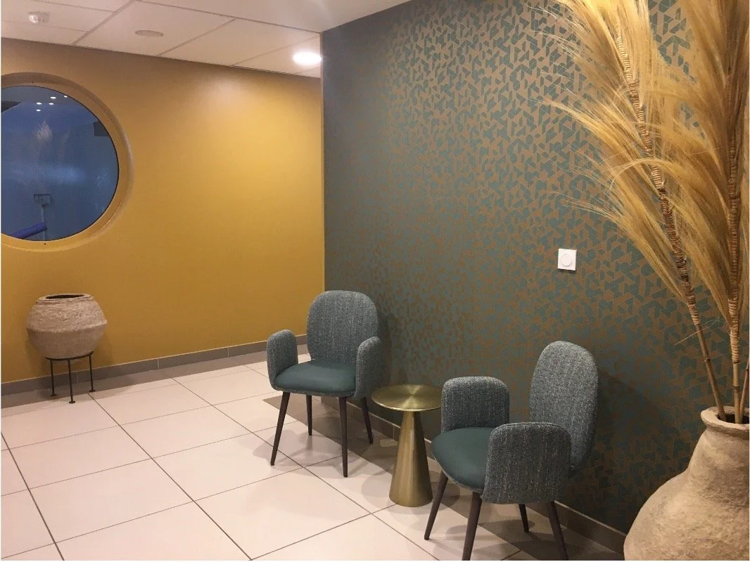 Couloir avec vase en terre cuite avec herbe de la pampa à l'intérieur, deux chaises bleus, une table de chevet en or, un mur couleur or et un mur couleur or et bleu.