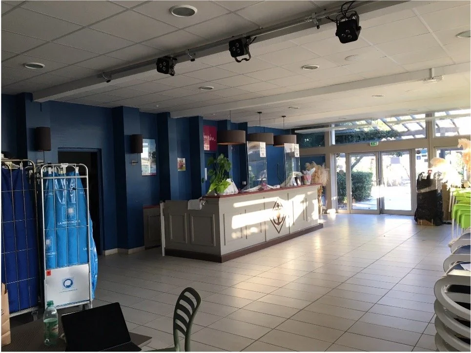 Comptoir d'accueil avec un motif d'ancre marine dessus, des suspensions. Une porte automatique vitré.