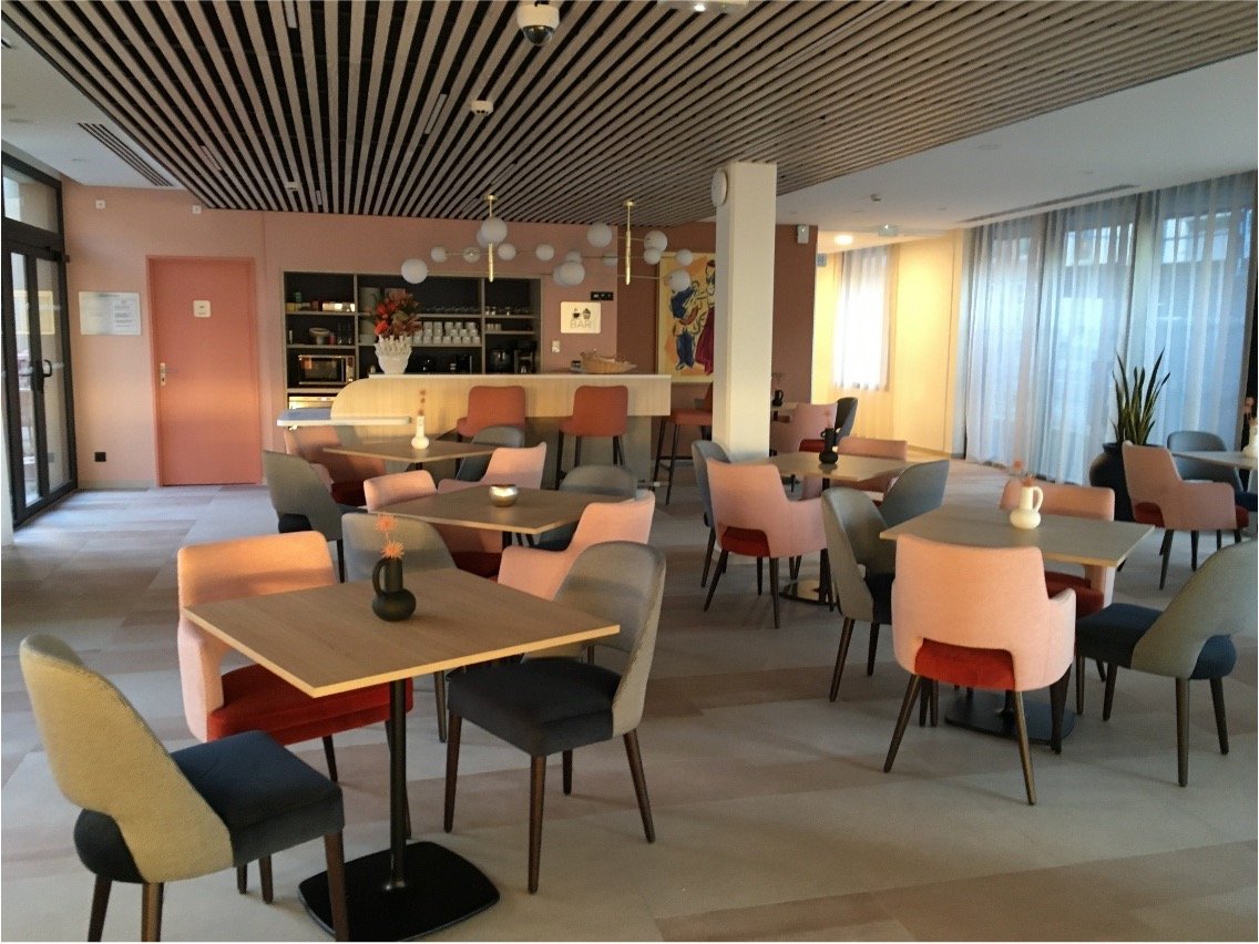 Bar moderne avec des mini vases noir et blanc, des chaises rose saumon et bleu foncé ainsi qu'un comptoir et rangement de bar