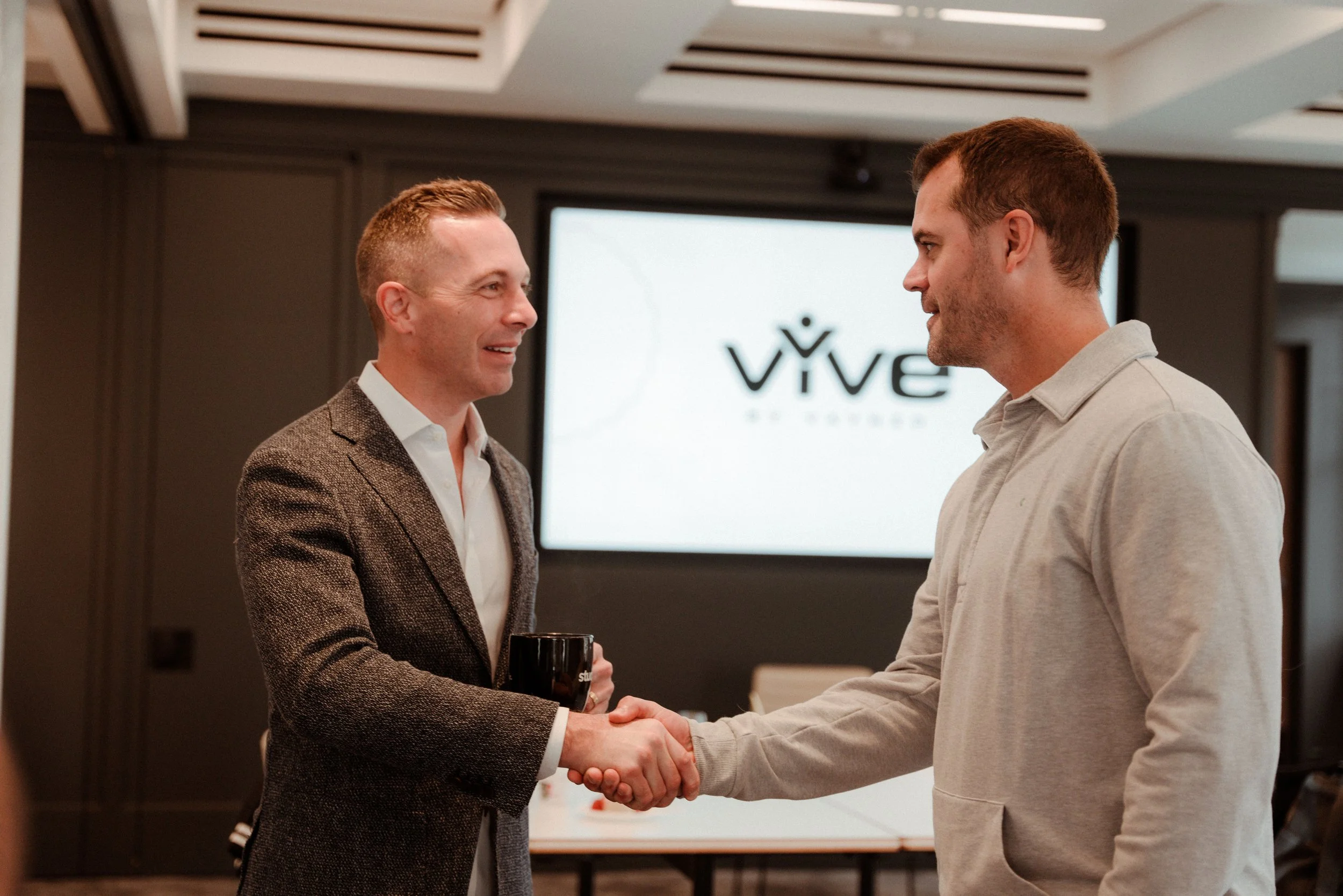 Members of vYve, called vYvers, shaking hands at a vYve Masterclass, with a 'VIVE' logo in the background.