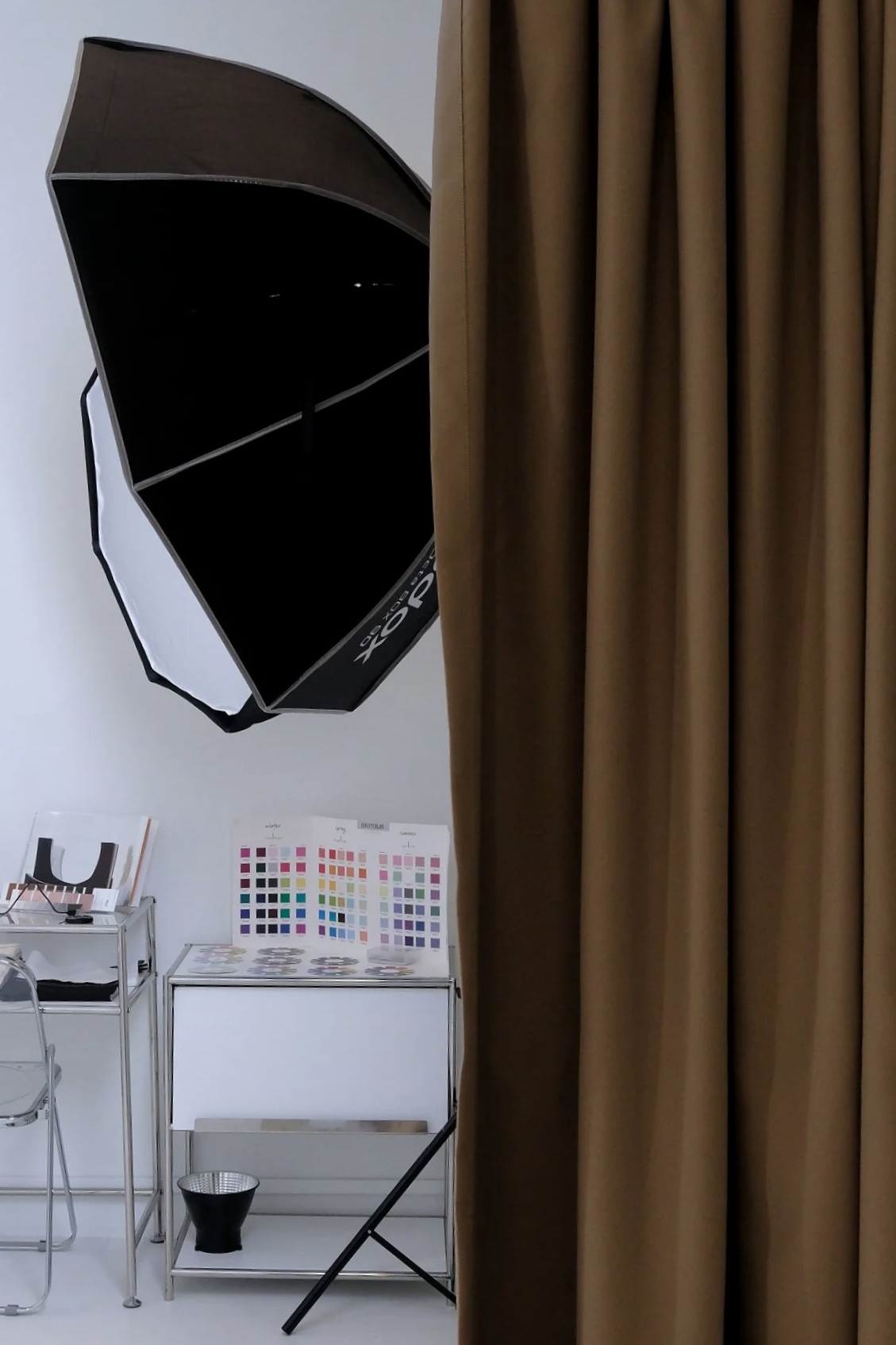 Photography studio with a large softbox light, color sample charts, and a brown curtain covering part of the scene.