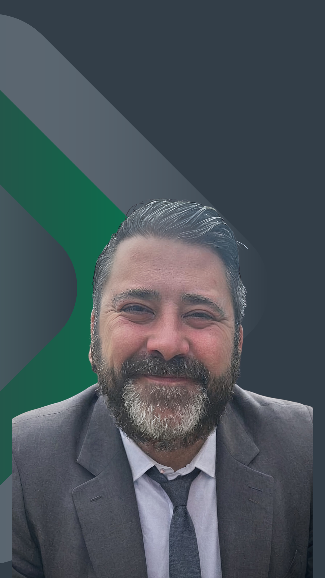 Portrait of a smiling man with a beard, wearing a gray suit, white shirt, and gray tie, against a dark background with geometric green and dark gray shapes.