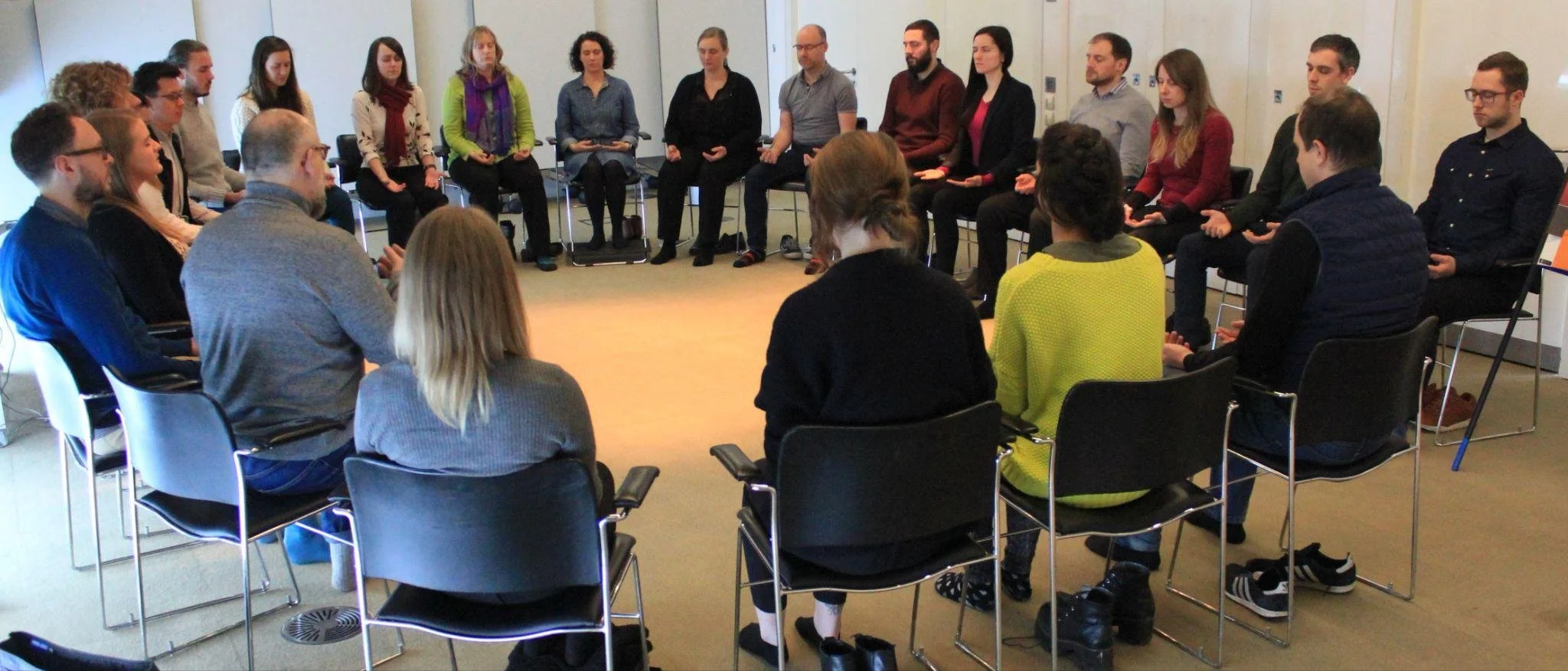 A group of people sitting in a circle in a conference room, participating in a discussion or workshop.