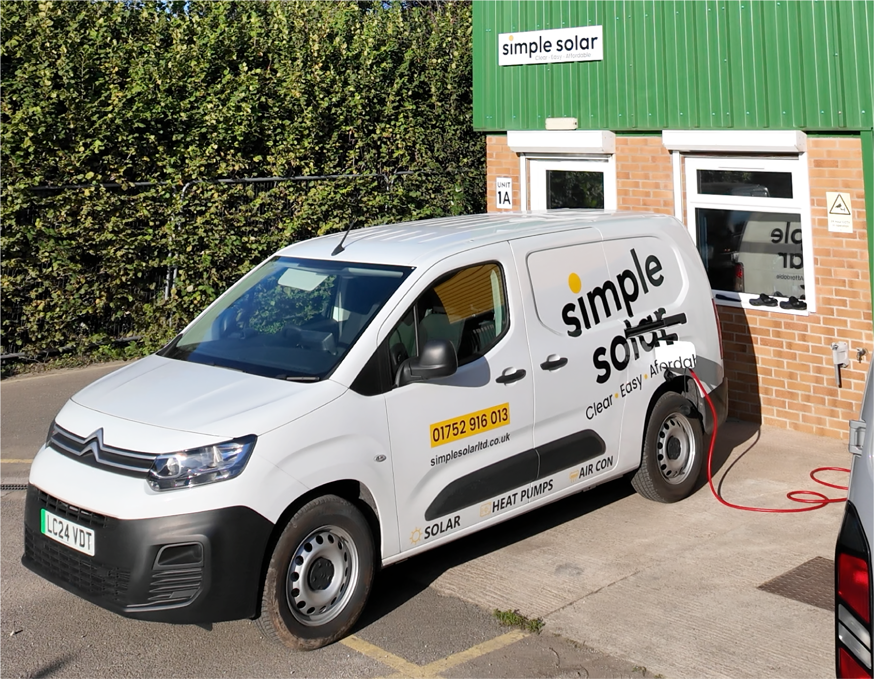 Simple Solar branded van parked outside the Simple Solar office, plugged in and charging.