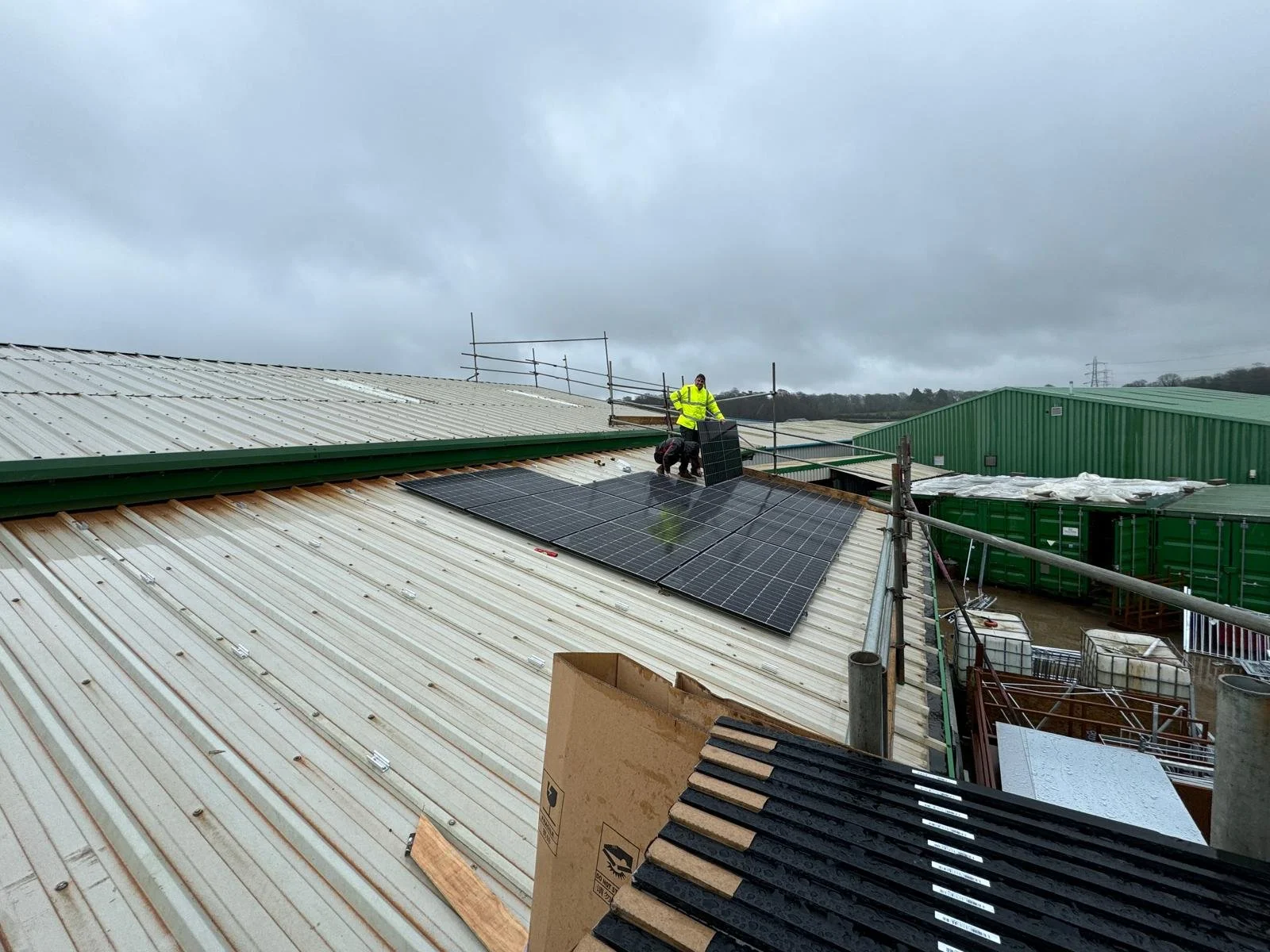 Installer fitting solar panels on a large industrial roof.