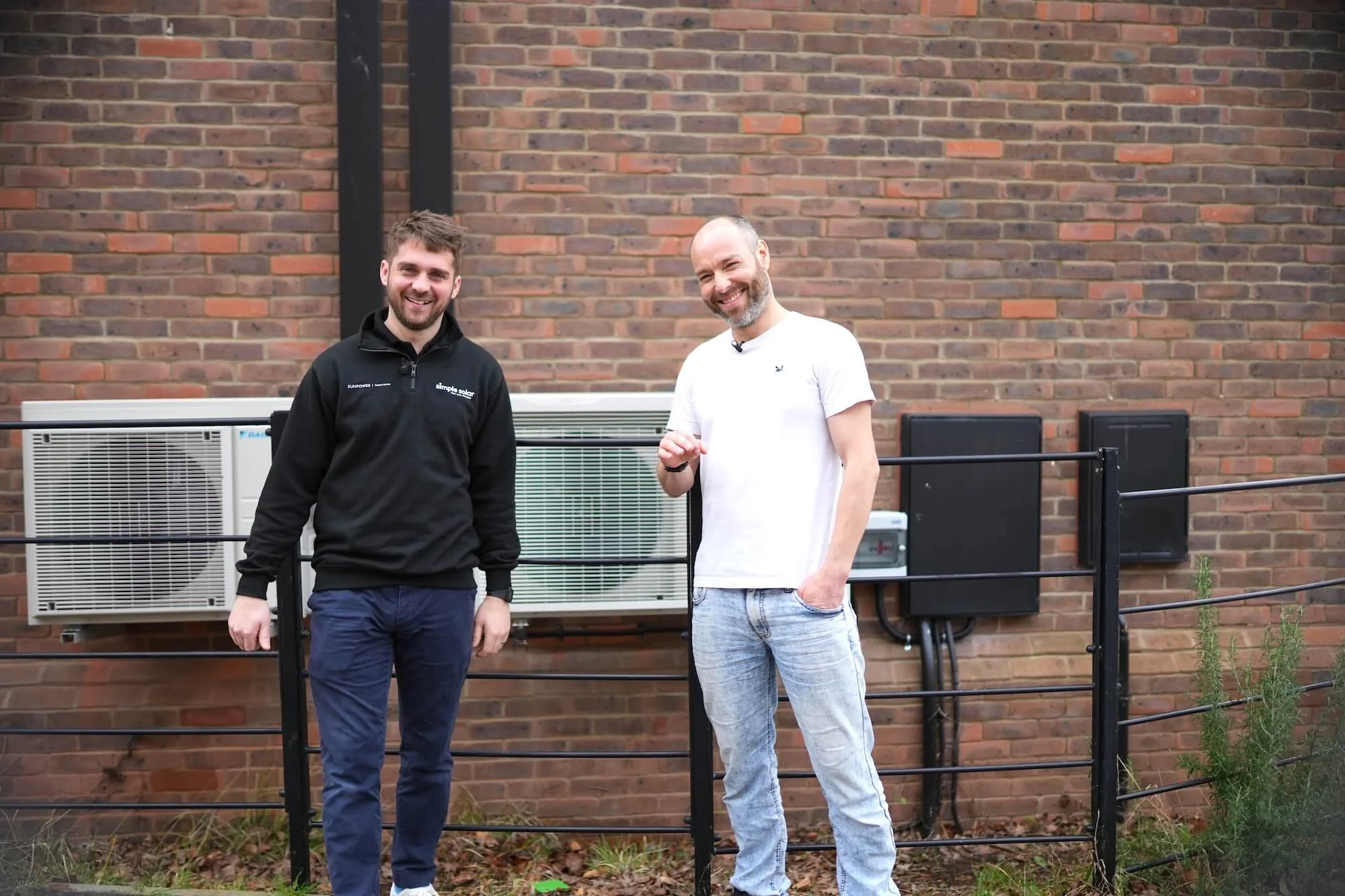 A Simple Solar engineer and a customer standing in front of an air source heat pump installation at a home near Ivybridge.