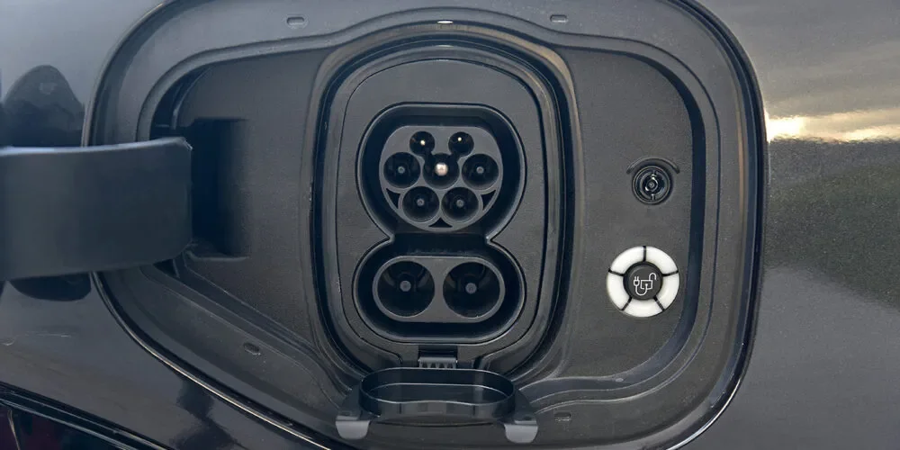 Close-up of an electric vehicle charging port with the connector socket and charge indicator light.