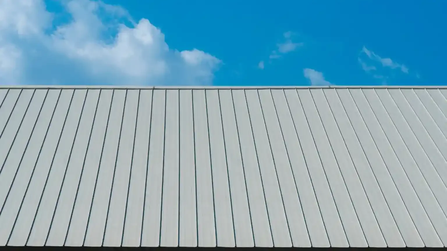 Standing seam metal roof under a blue sky with a few clouds.