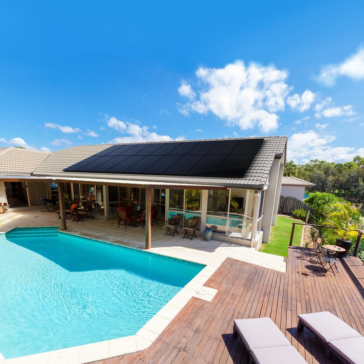 Modern single-story house in Melbourne with tiled roof featuring the Sunpower Performance 7 solar panels, a large array of sleek all-black solar panels, overlooking a swimming pool and outdoor patio area on a sunny day with blue sky.