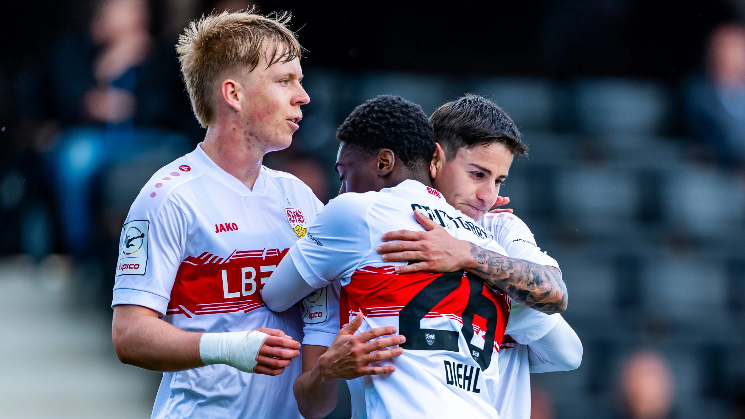 Fußballspieler in weißen und roten Trikots umarmt sich nach dem Spiel auf dem Spielfeld.