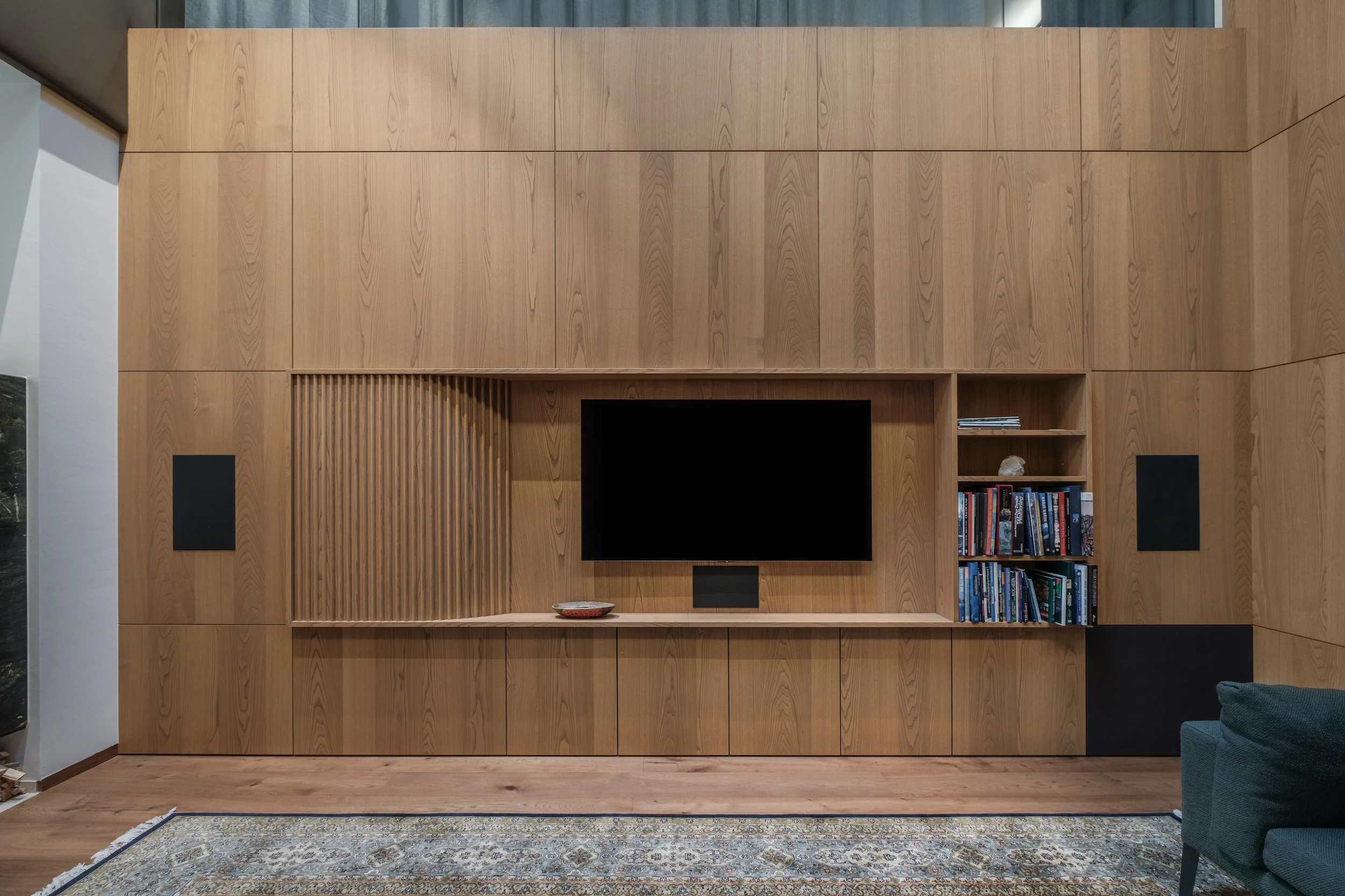 Hölzerne Wand mit eingebautem Fernseher, Bücherregal und Dekoration in einem Wohnzimmer.