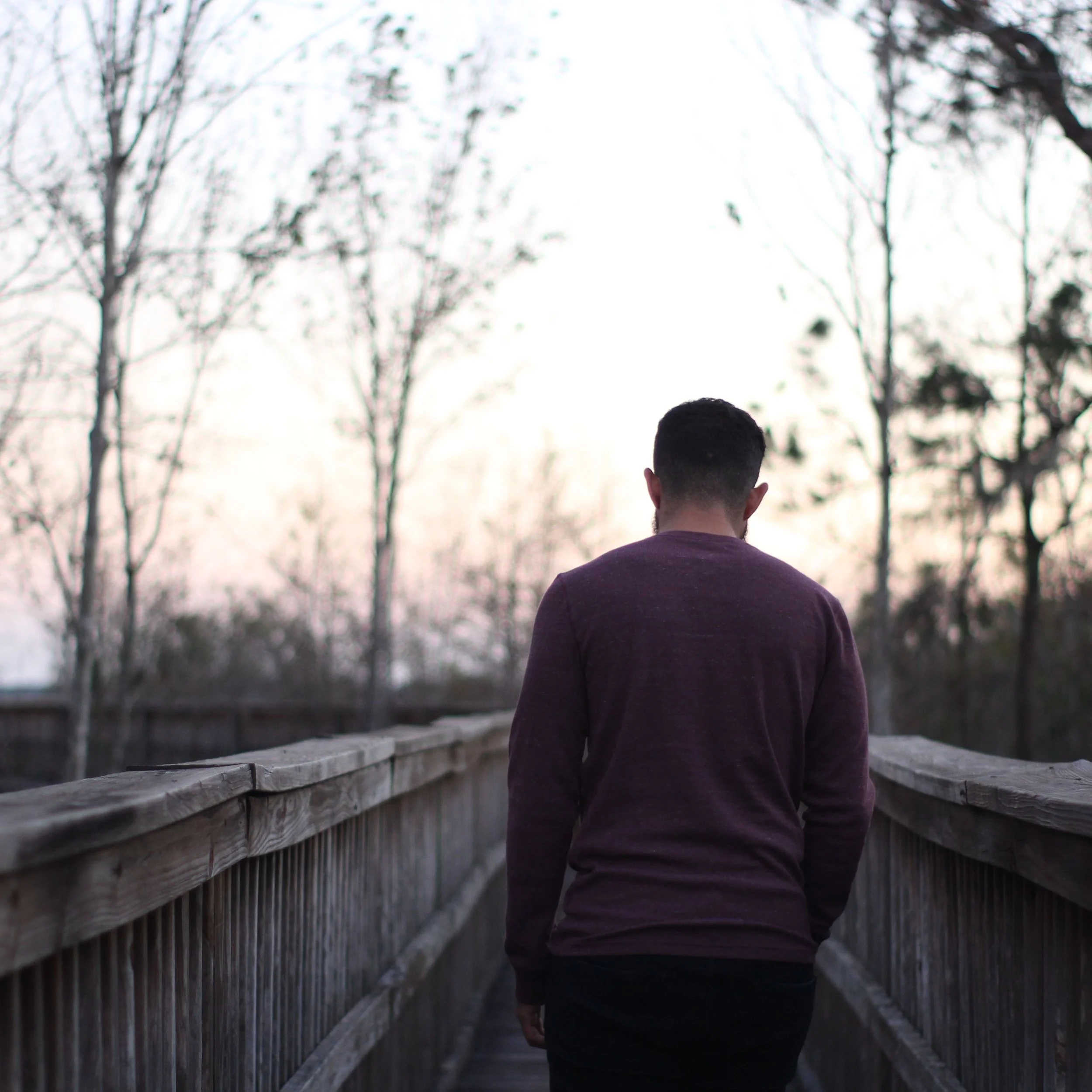 A man walks along a wooden bridge in a serene dusk setting. Credit: Joice Rivas