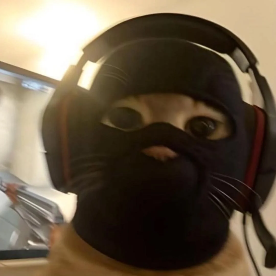 Close-up of a person wearing a black face mask, a helmet, and headphones, with only their eyes visible.