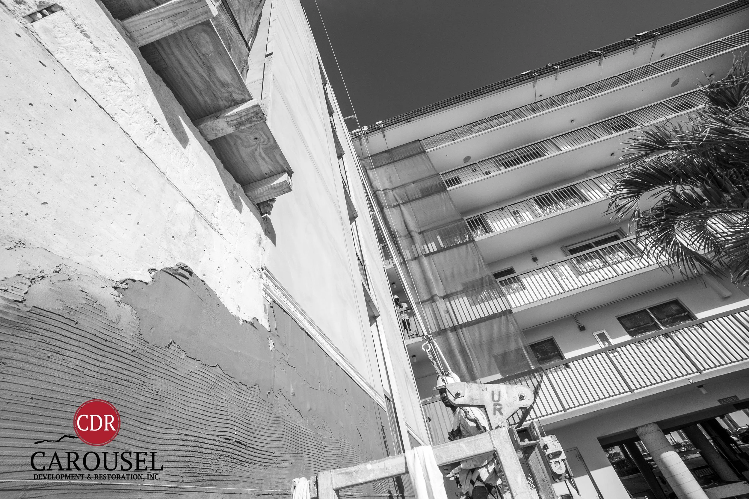 Carousel employee repairing stucco on the side of a building