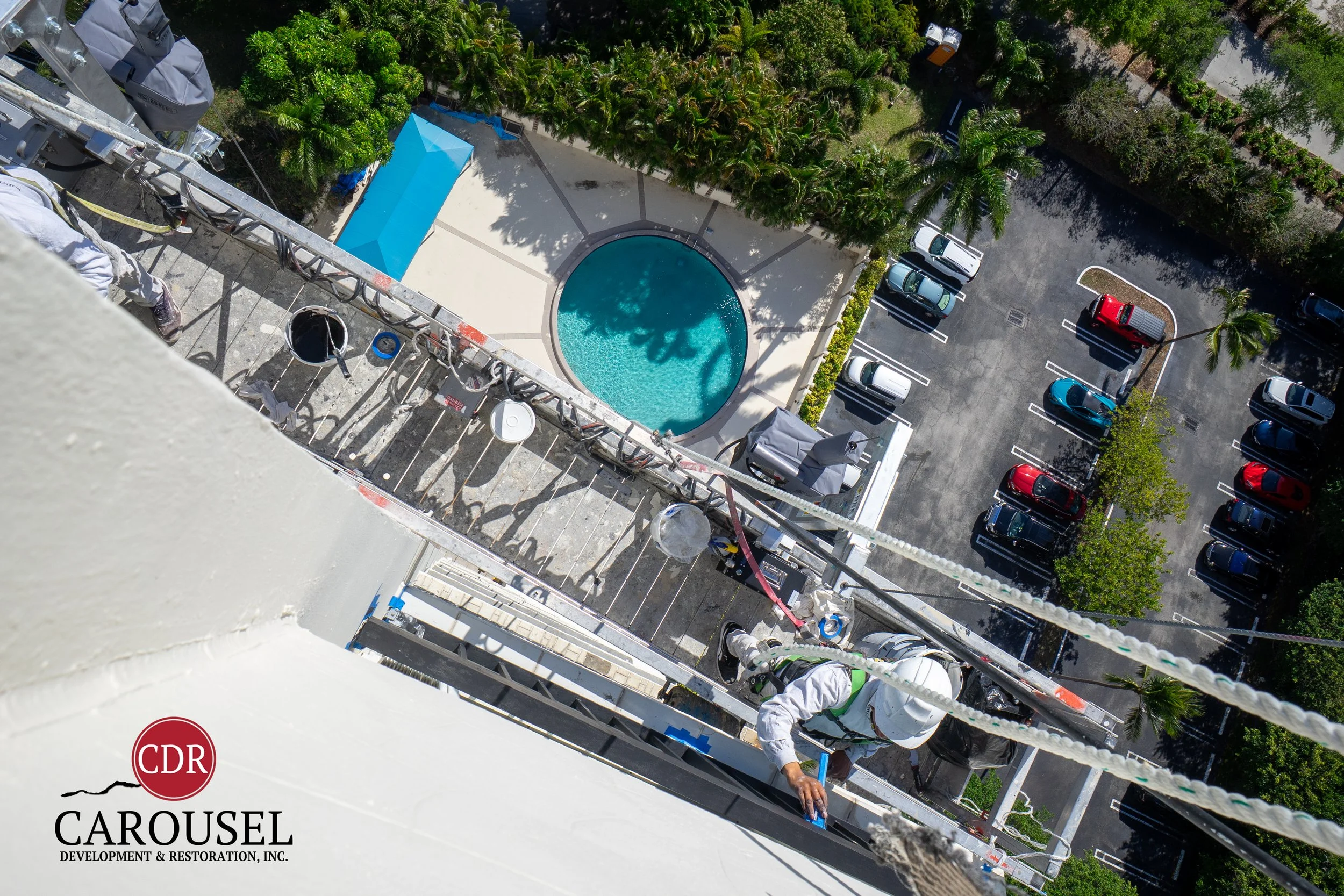birdseye view of scaffolding and carousel employee painting side of high rise building