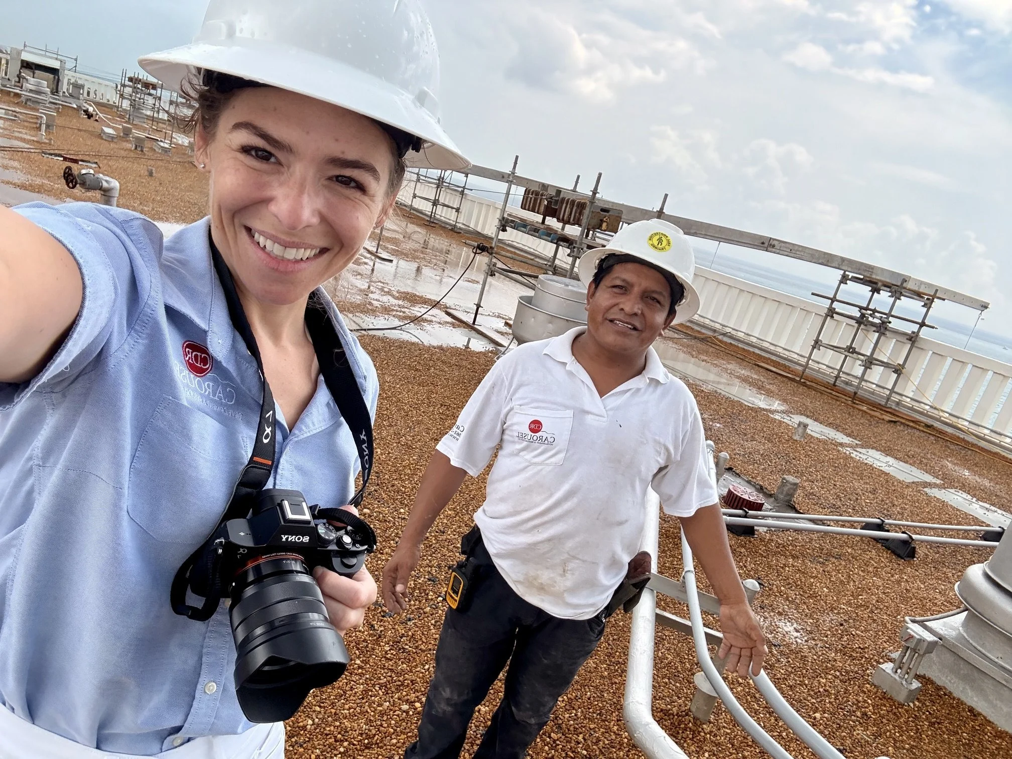 Gabriella Bianchini and another Carousel Employee On the rood of an ocean-front building with scaffolding behond them
