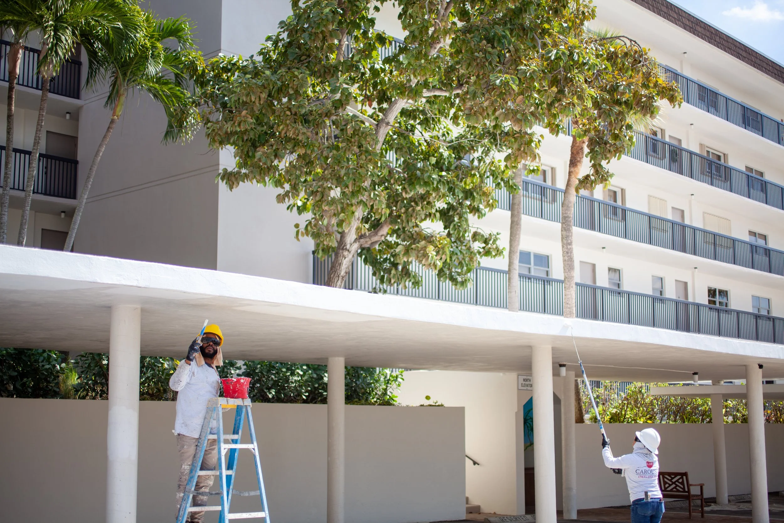 Two Carousel employees paitning an exterior flat roof of a high rise building