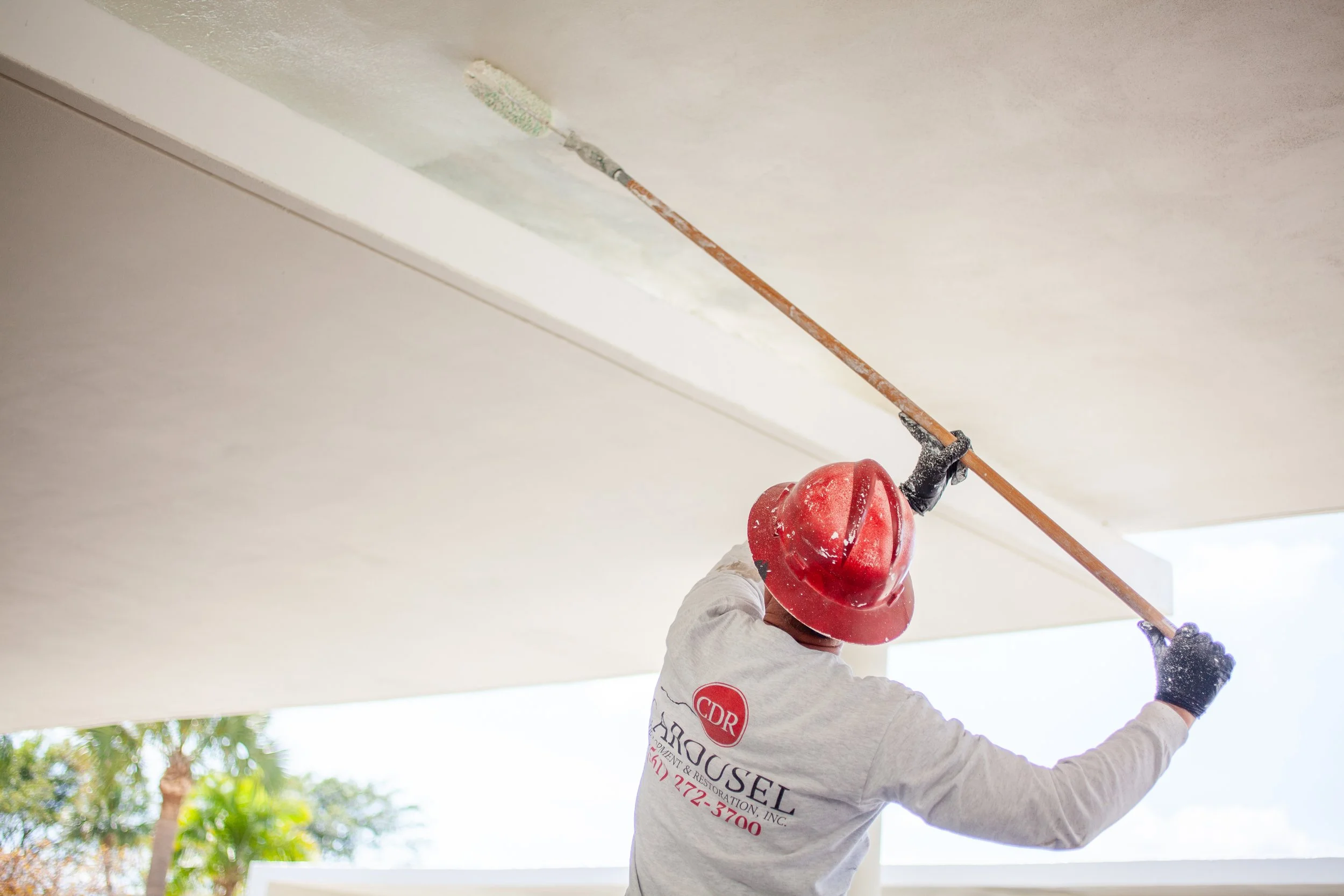 Carousel employee painting a ceiling with a roller
