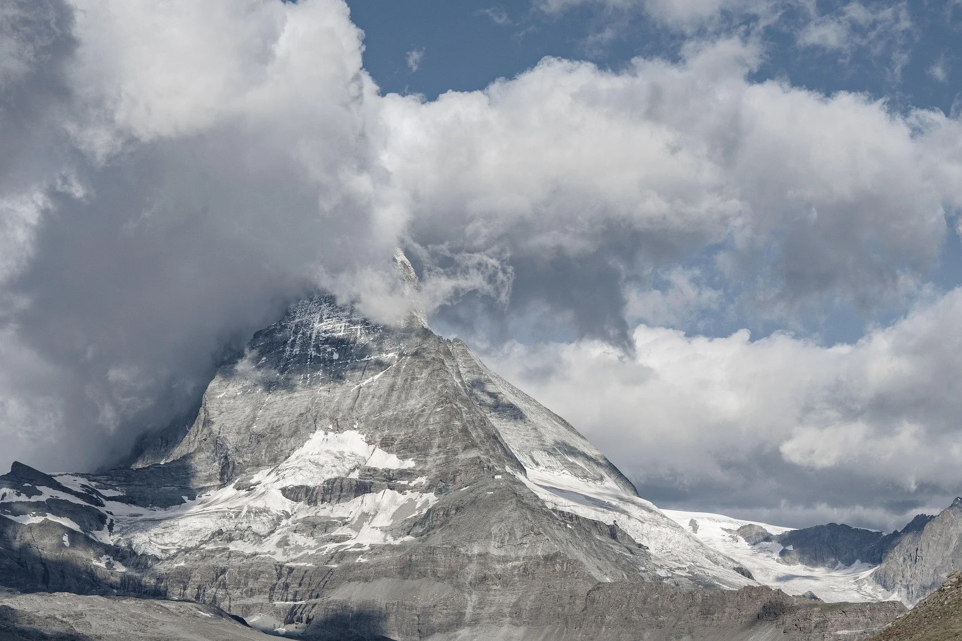 Snow-capped mountain peak with clouds around it.