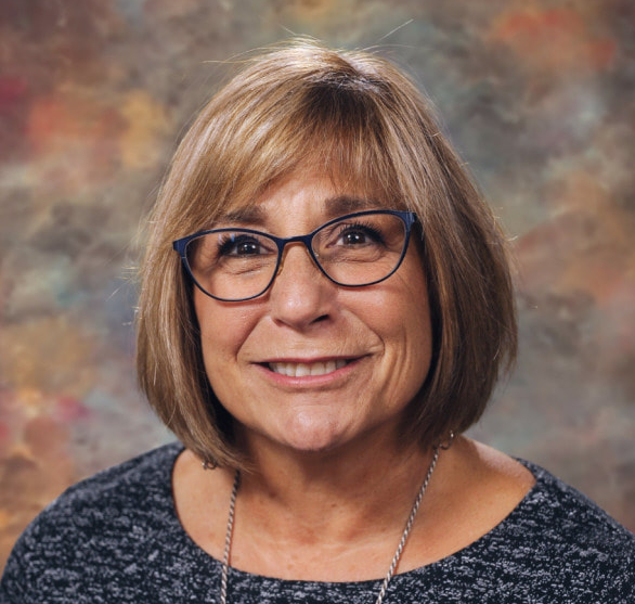 A photograph of a person with glasses smiling at the camera.