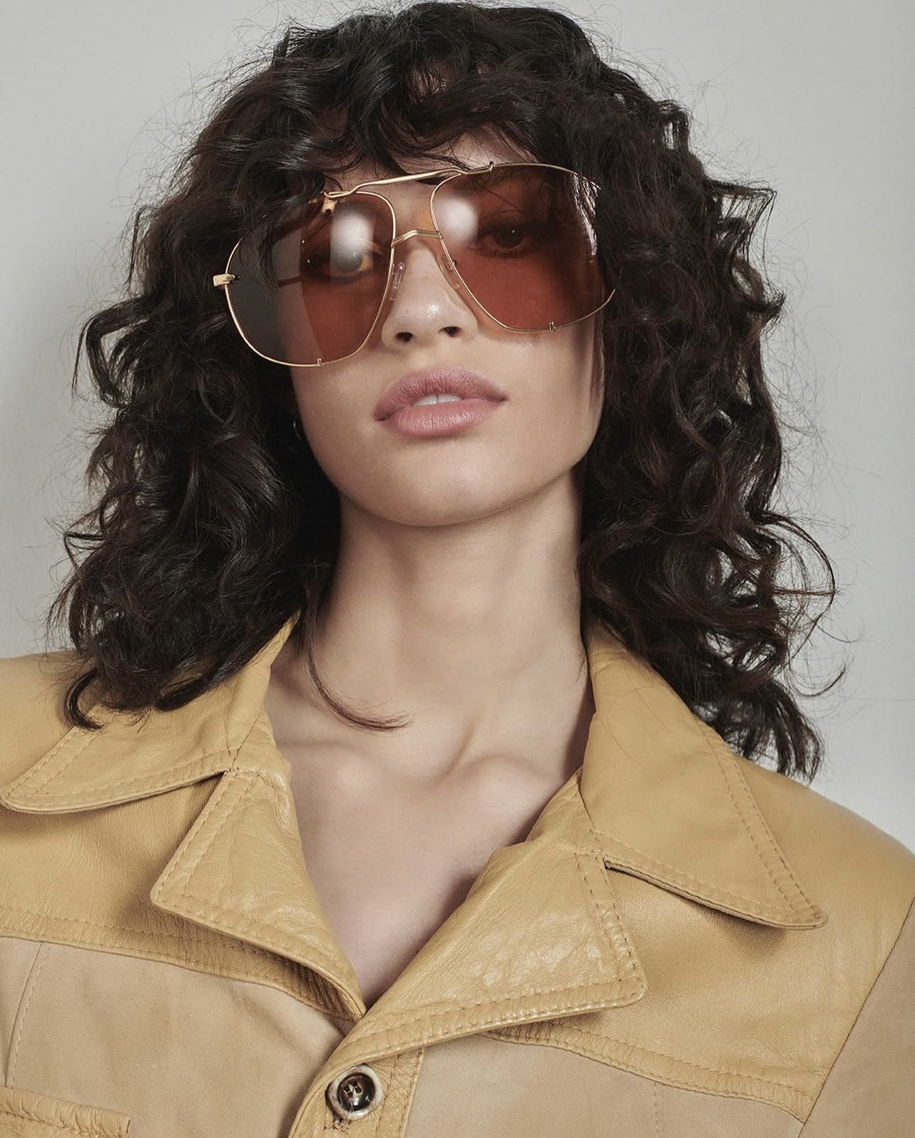 A woman wearing large, brown-tinted sunglasses and a tan leather jacket.