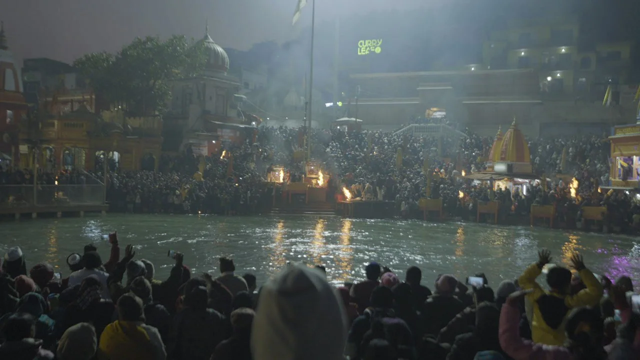 Traditional Indian religious setup with colorful rangoli designs, incense, floral offerings, candles, and a framed photograph, likely for a shrine or ceremony.