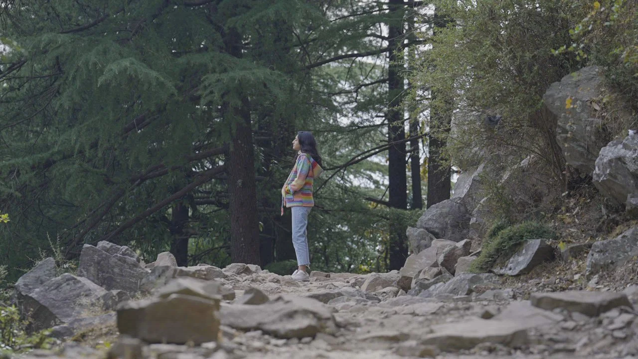 Priyanka Lugani standing on a rocky mountain path in the cedar forests of Dharamshala.