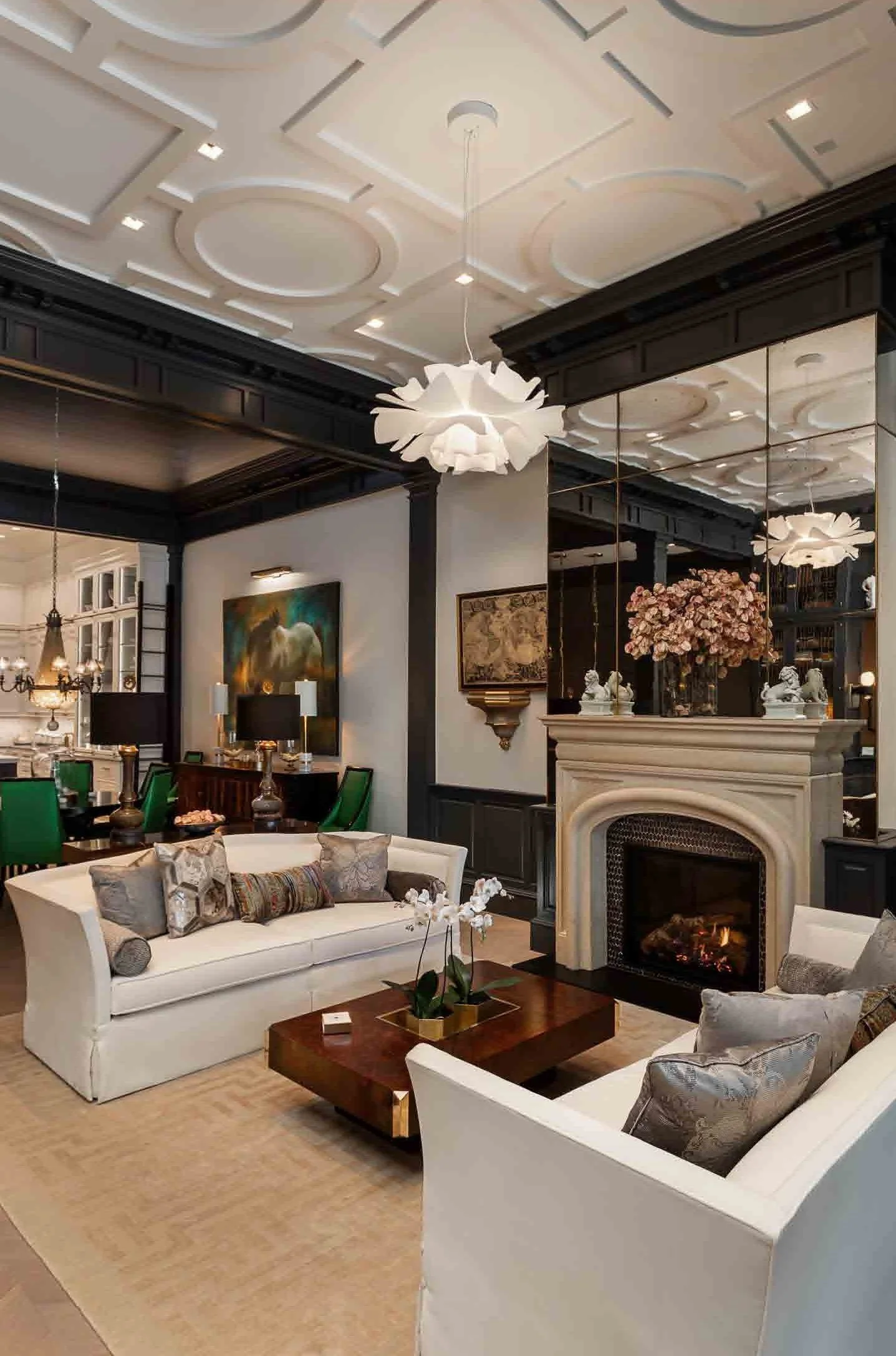 Elegant living room with white sofas, a fireplace, a wooden coffee table, floral decor, and upscale lighting fixtures.