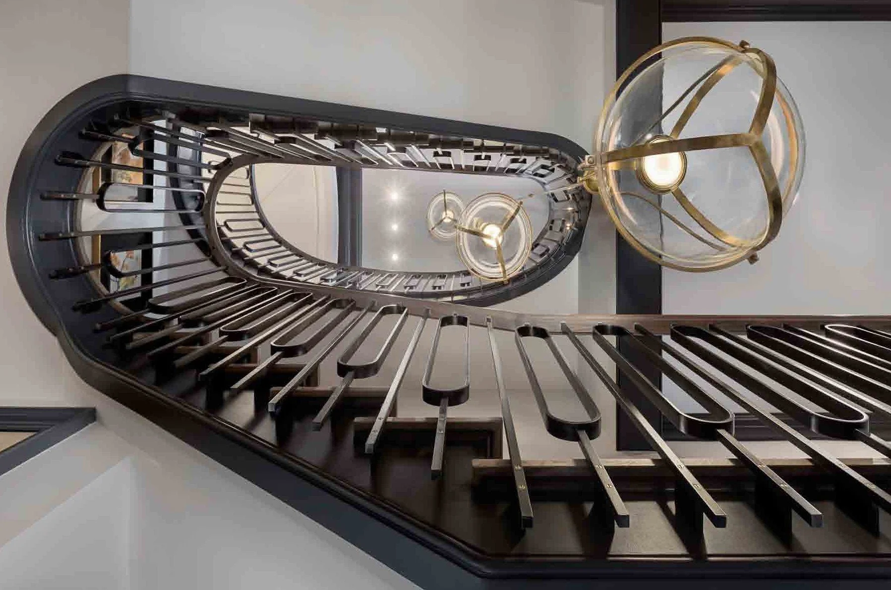 Looking up the interior staircase with dark wooden steps and chandelier with glass and gold accents.