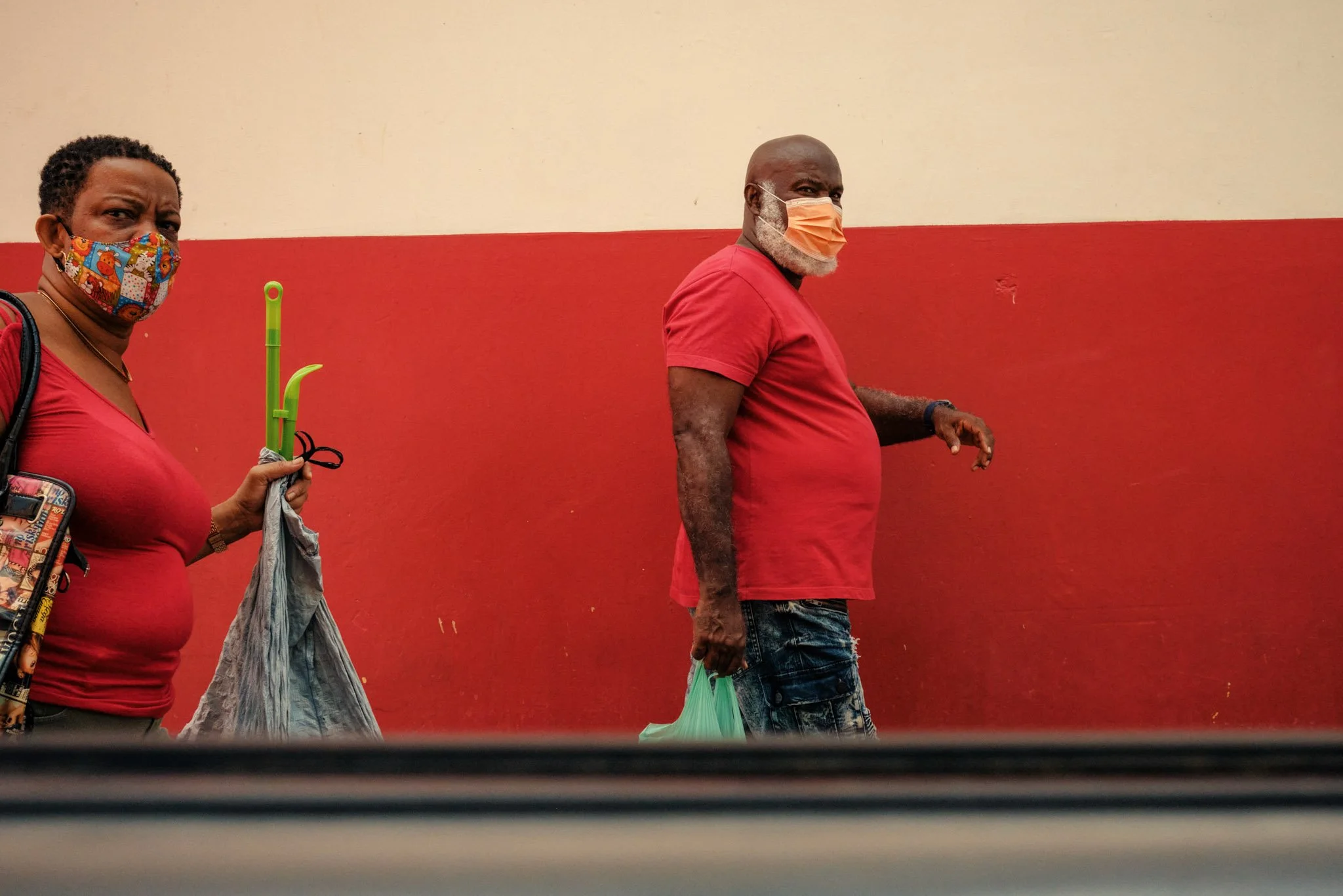 BARBADOS_A-STREET-PHOTO-OF-A-COUPLE-DRESSED-IN-RED-WALKING-ALONGSIDE-A-RED-WALL.jpg
