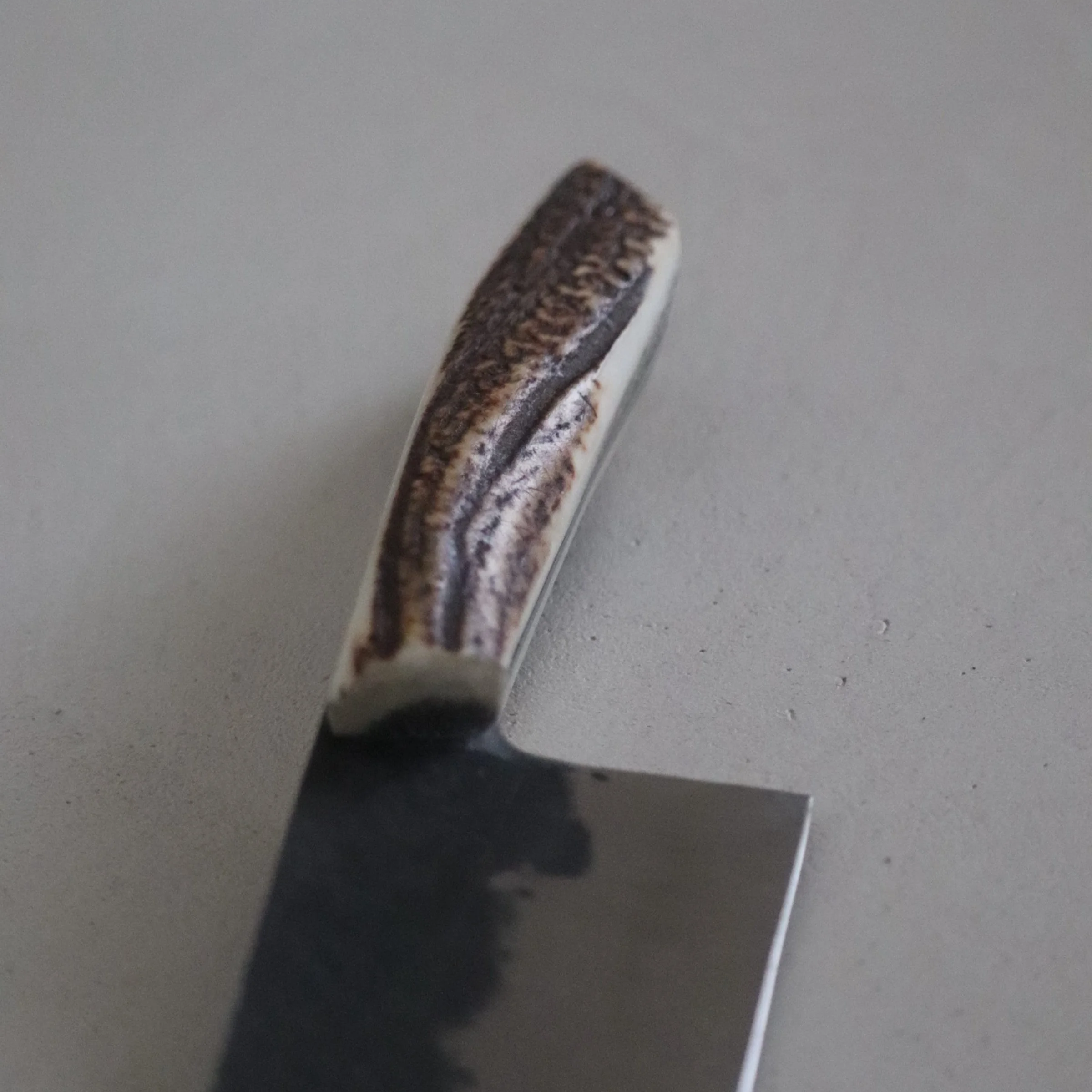 Close-up of a straight razors with a textured handle and a shiny blade, resting on a flat surface.