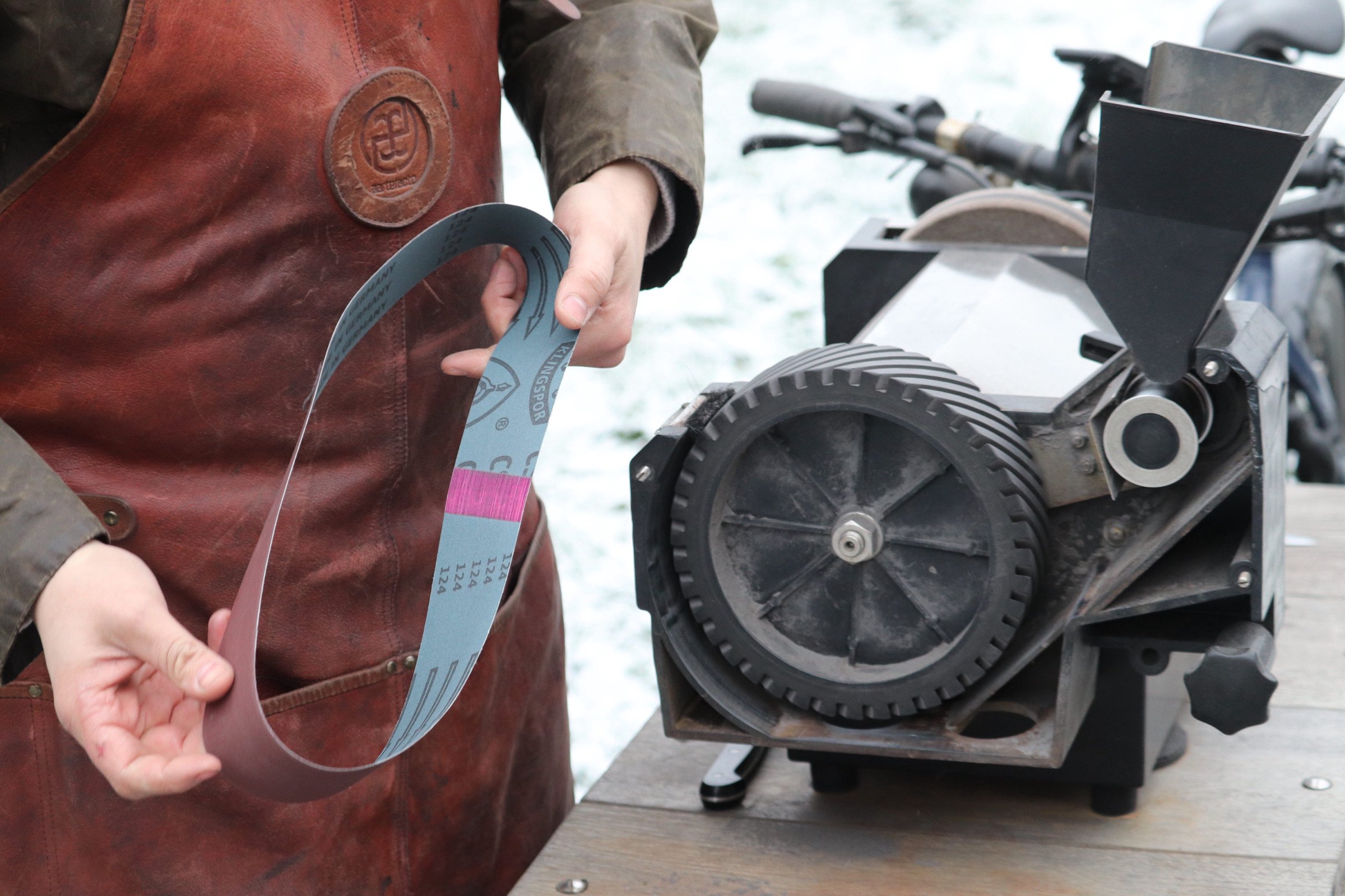 Person operating a laminating machine to process a flexible printed circuit, with a snowy outdoor background.